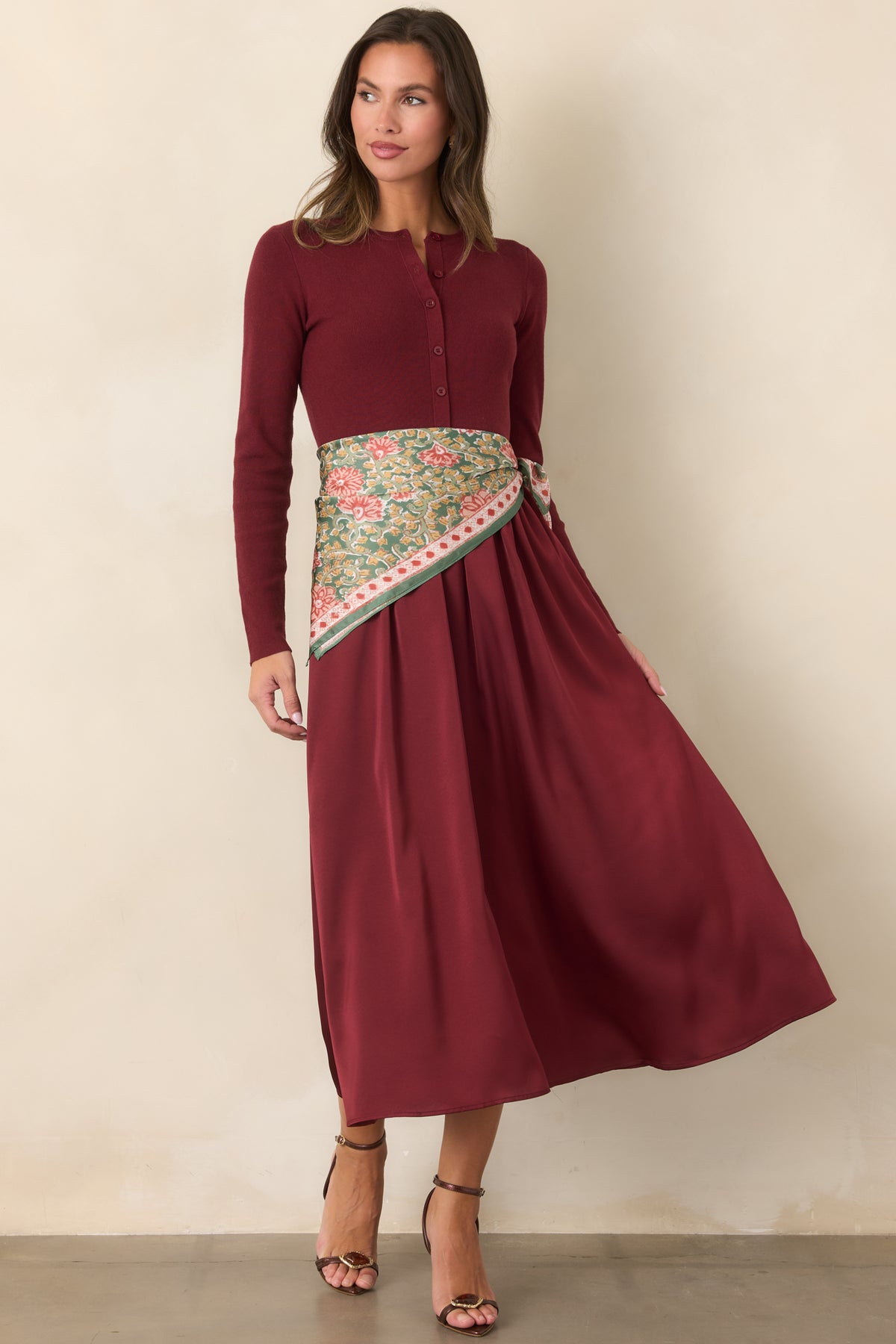 Burgundy dress featuring a fitted knit bodice, long sleeves, defined waist, and gently flared satin skirt.
