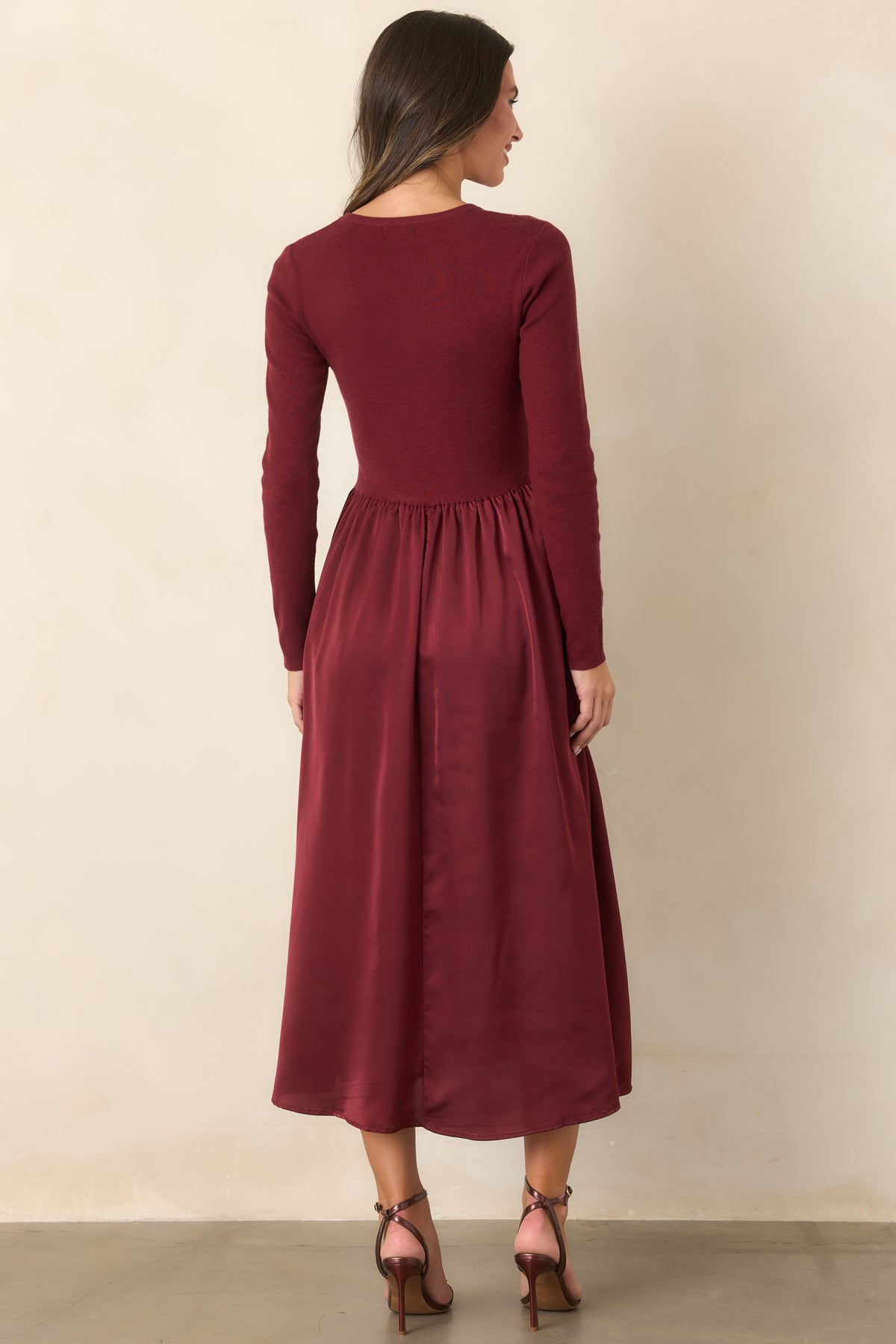 Rear of the burgundy midi dress showing the knit bodice, defined waist, and flowing satin skirt.
