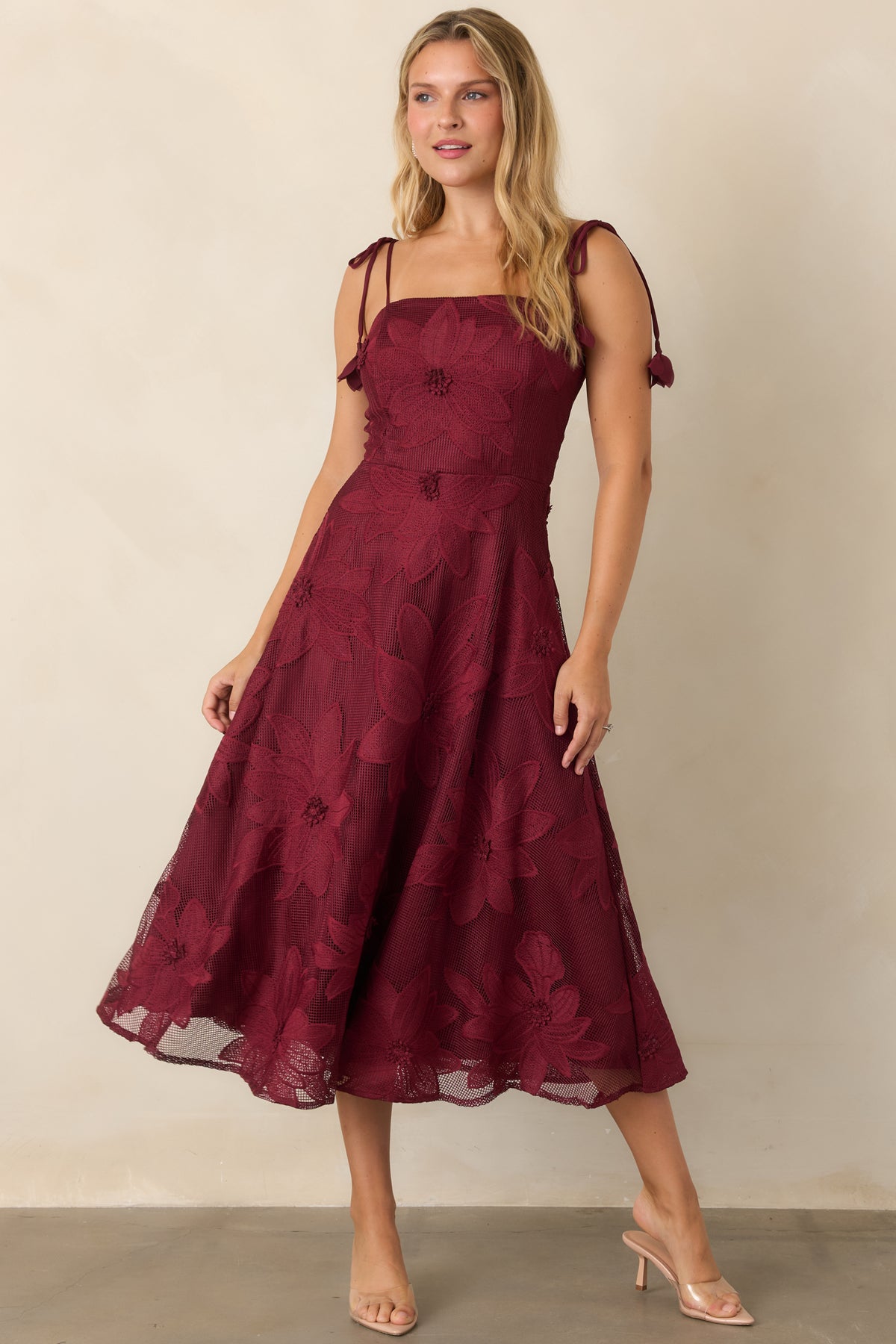 Fitted burgundy lace dress with adjustable tie straps and a softly sweeping skirt.