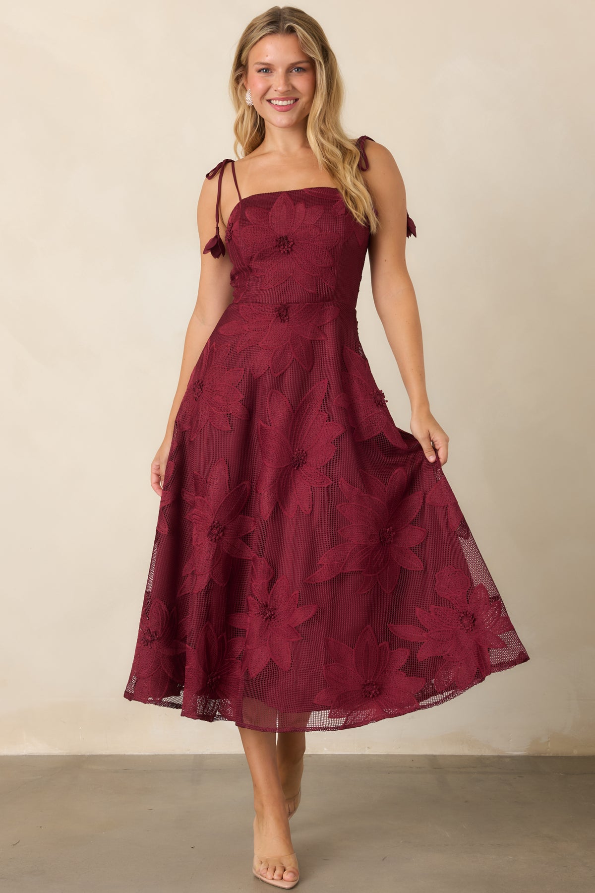 Burgundy lace midi dress featuring a straight neckline, fitted bodice, and sweeping A-line skirt.
