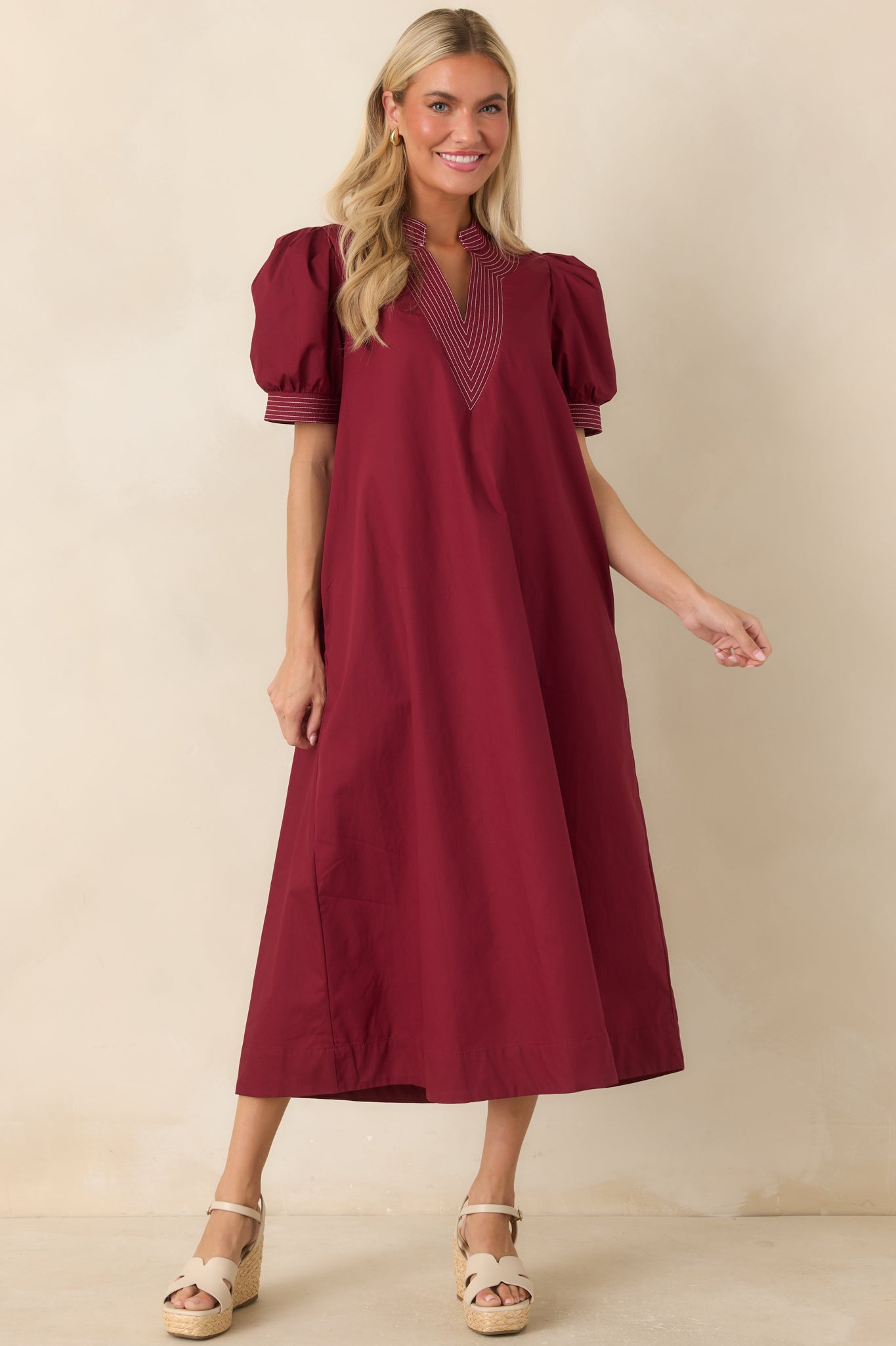 Burgundy midi dress featuring a structured split neckline, contrast stitching, and short puff sleeves.