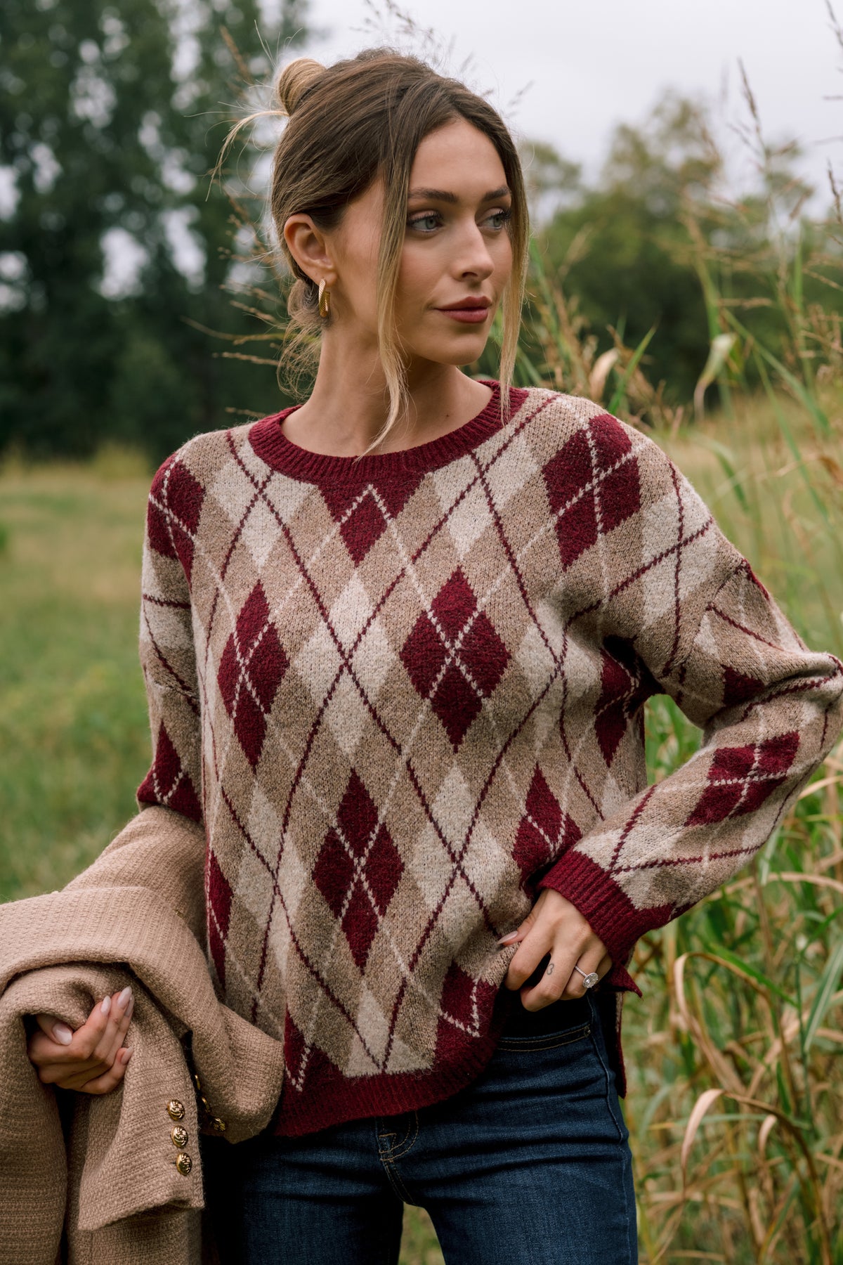 Burgundy knit sweater featuring an allover multi-color argyle pattern, relaxed fit, and ribbed crew neckline.