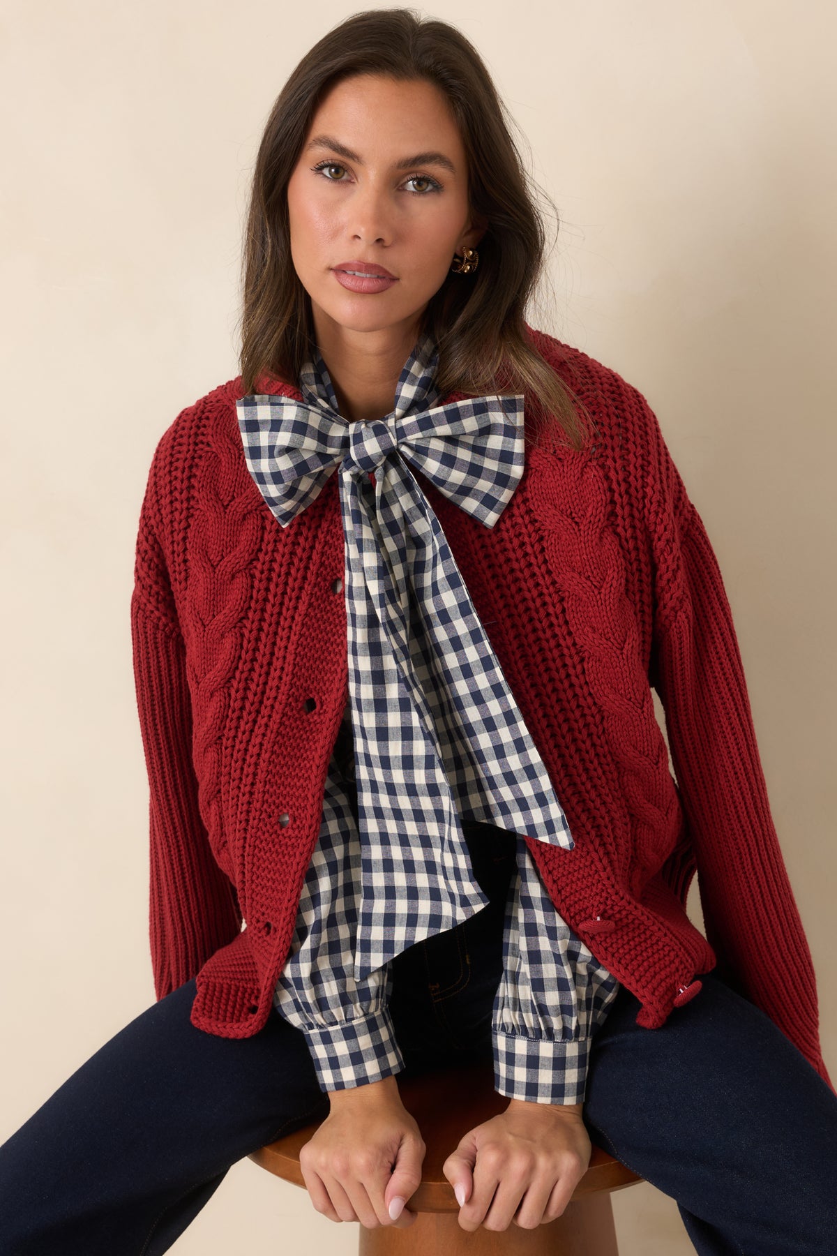 Burgundy cardigan with prominent cable-knit texture framing the button-front closure.