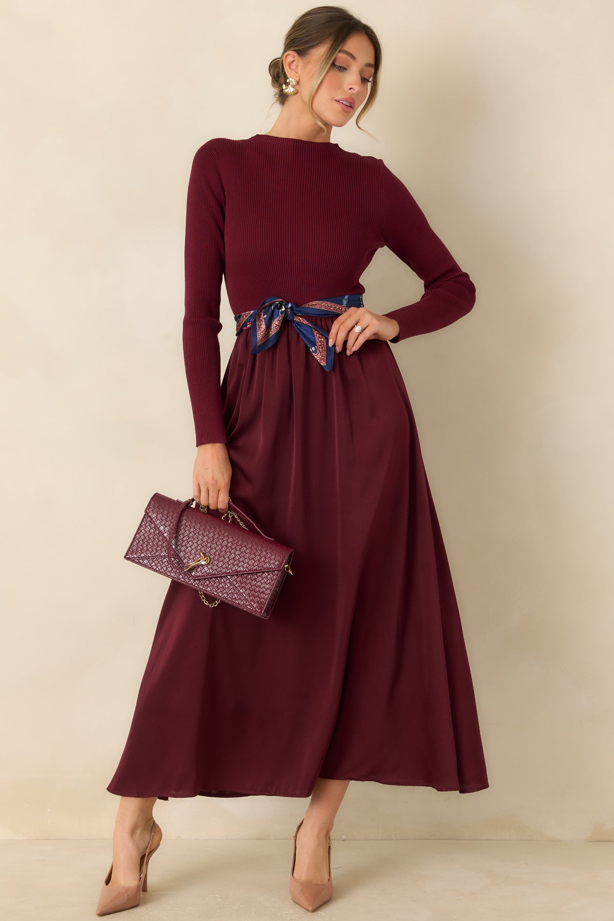 Burgundy knit and satin dress with a textured ribbed bodice and a smooth, lustrous midi skirt.