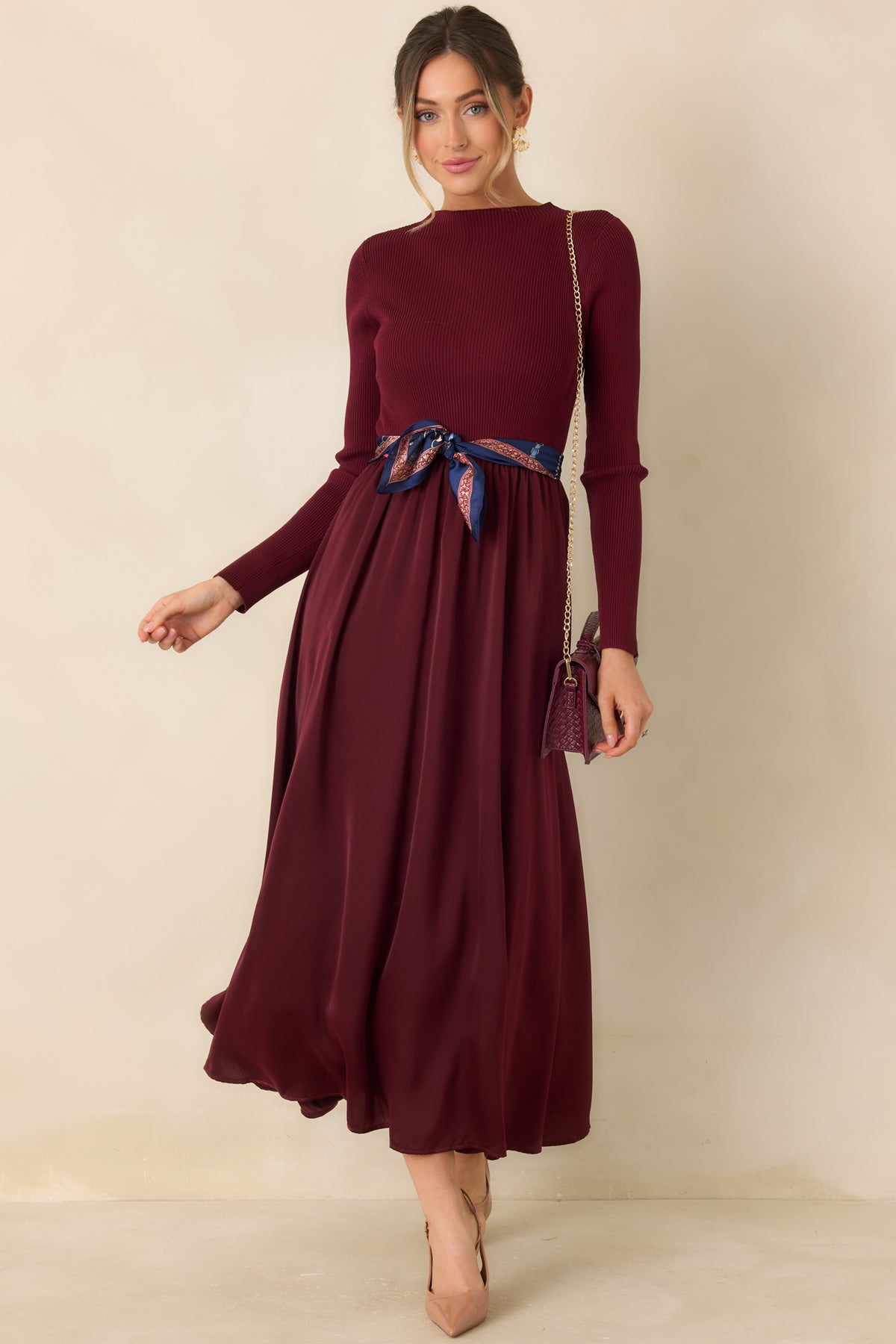 Burgundy fit-and-flare dress with a ribbed mock-neck bodice and gathered satin fabric at the waist.