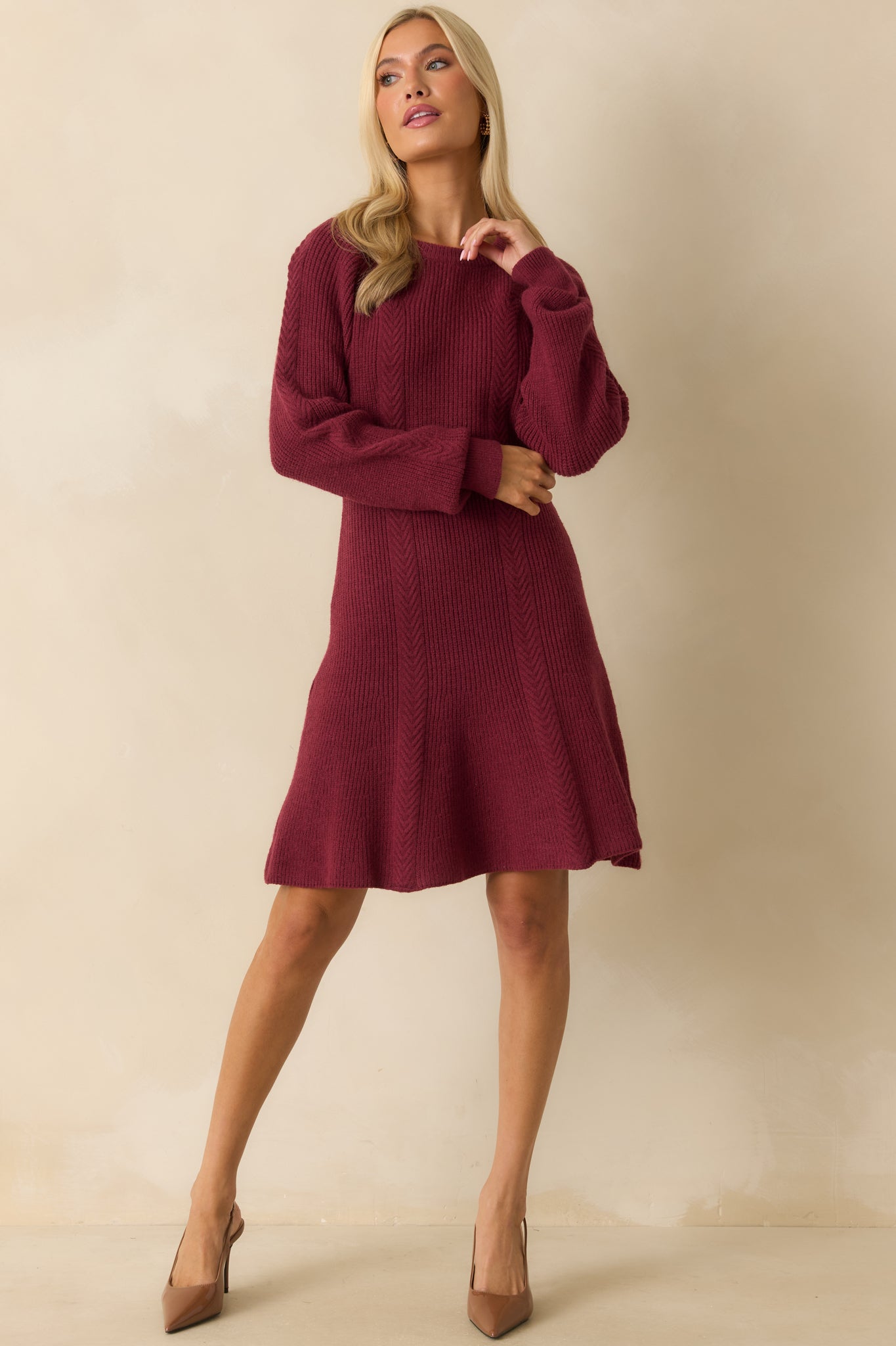 Burgundy ribbed knit sweater dress with a crew neckline, fitted bodice, long sleeves with ribbed cuffs, and a flared hem.