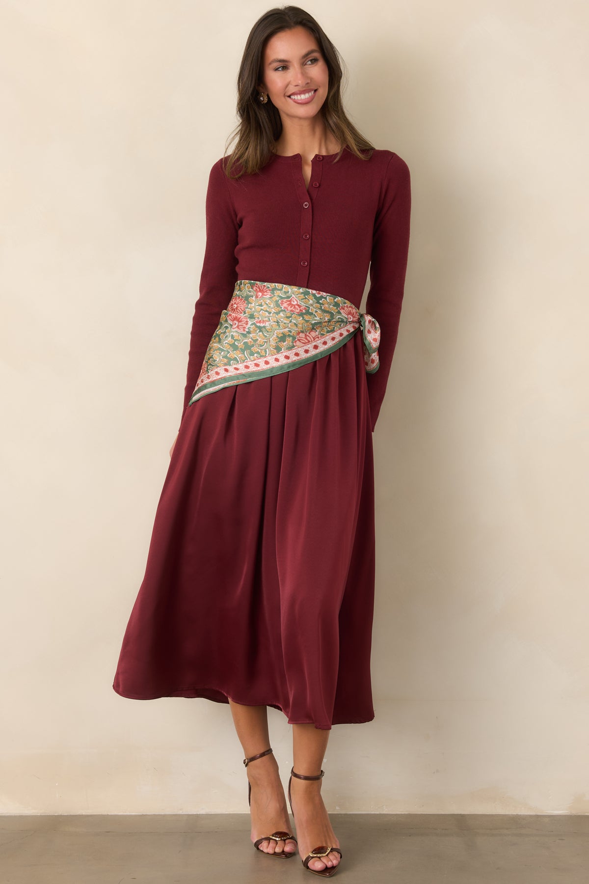 Burgundy midi dress showcasing a classic round neckline, long knit sleeves, and softly gathered satin skirt.
