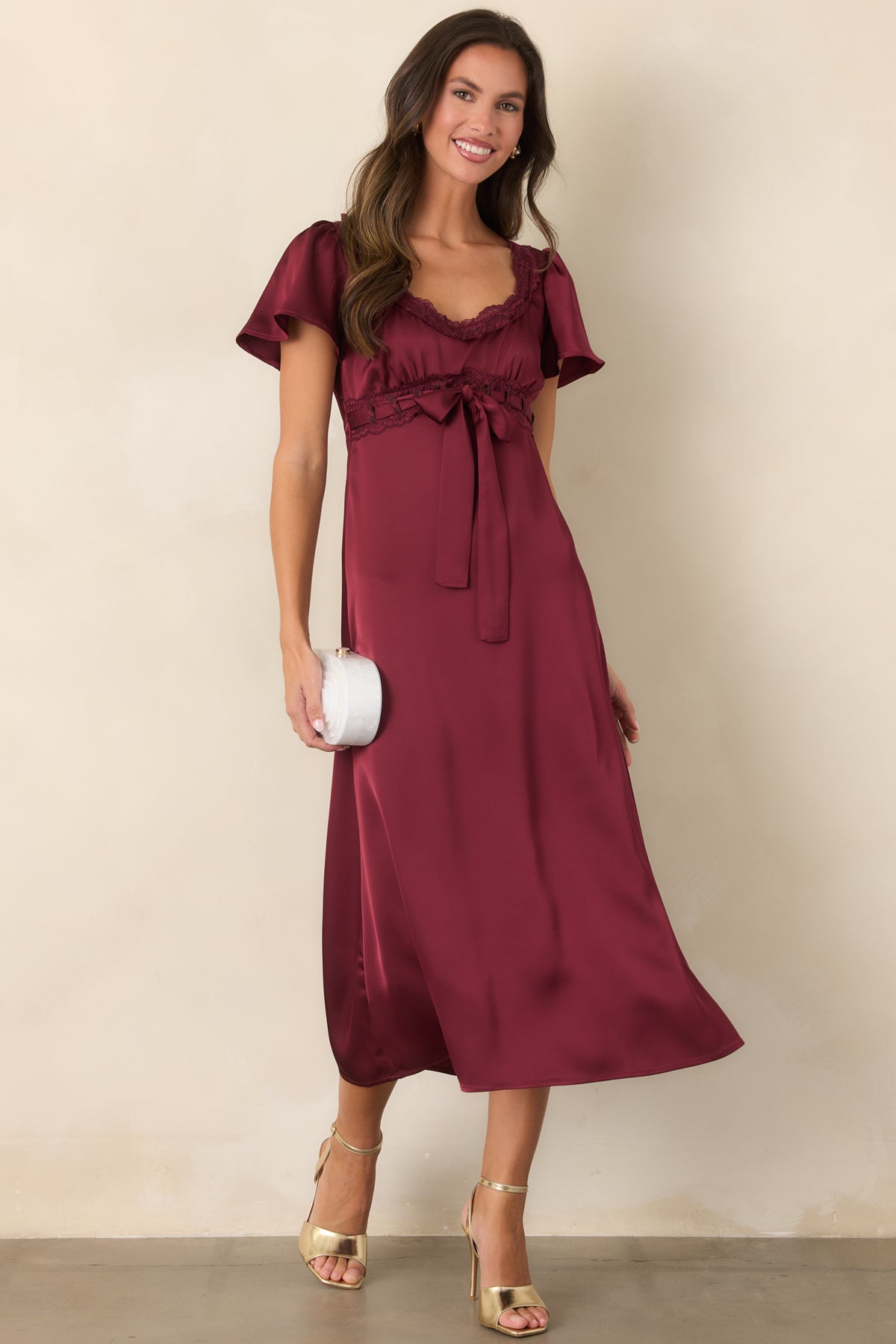 Rich burgundy satin midi dress featuring a scalloped lace neckline, flutter sleeves, and a gathered empire waist.