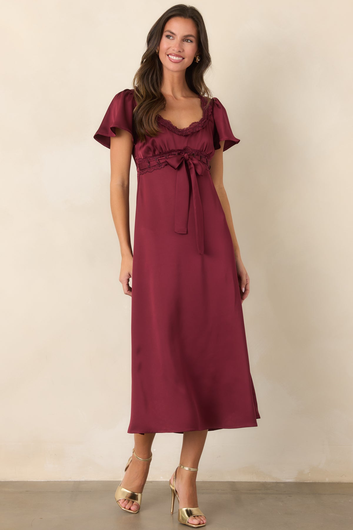 Rich burgundy satin dress with a defined ribbon waist, gathered skirt, and subtle allover sheen.