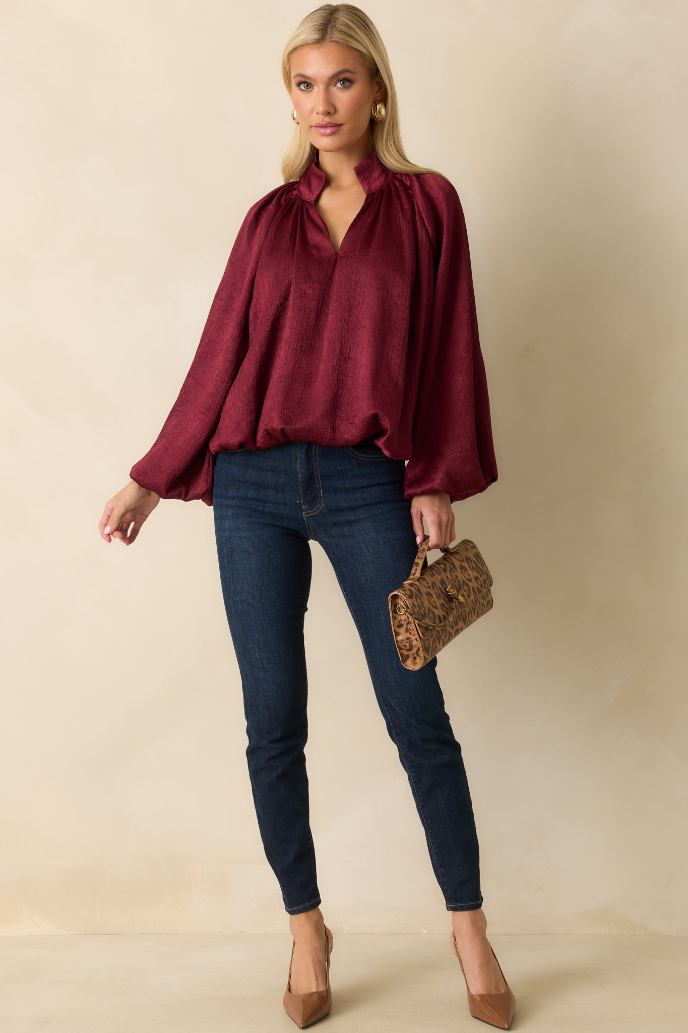Relaxed-fit burgundy satin V-neck top with subtle texture and billowy peasant sleeves.