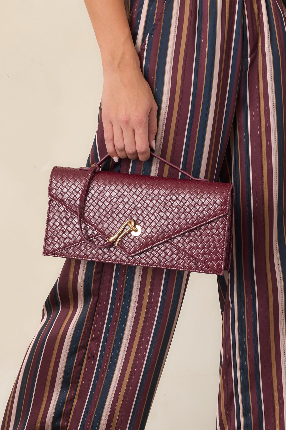 Structured burgundy envelope clutch featuring a slender top handle and pointed flap front.