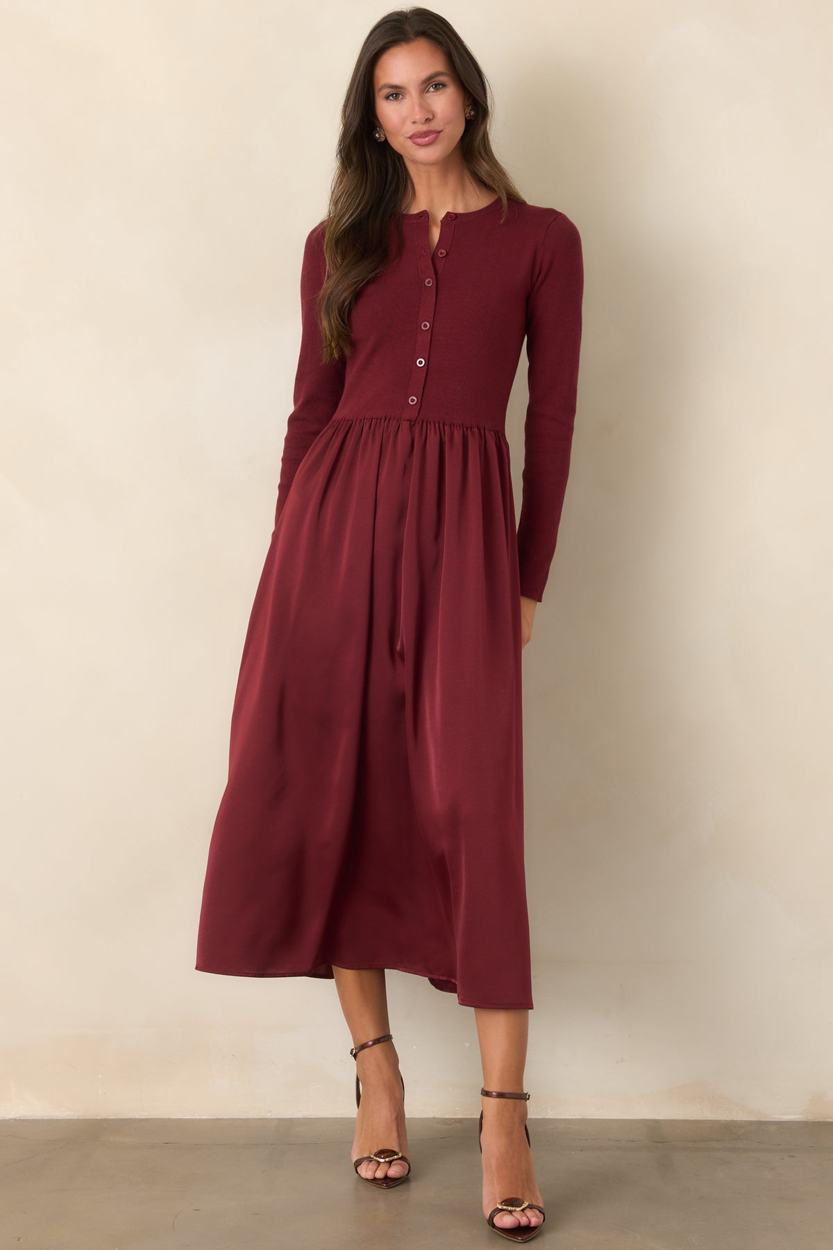 Burgundy midi dress featuring a structured knit top and lustrous satin skirt with graceful movement.
