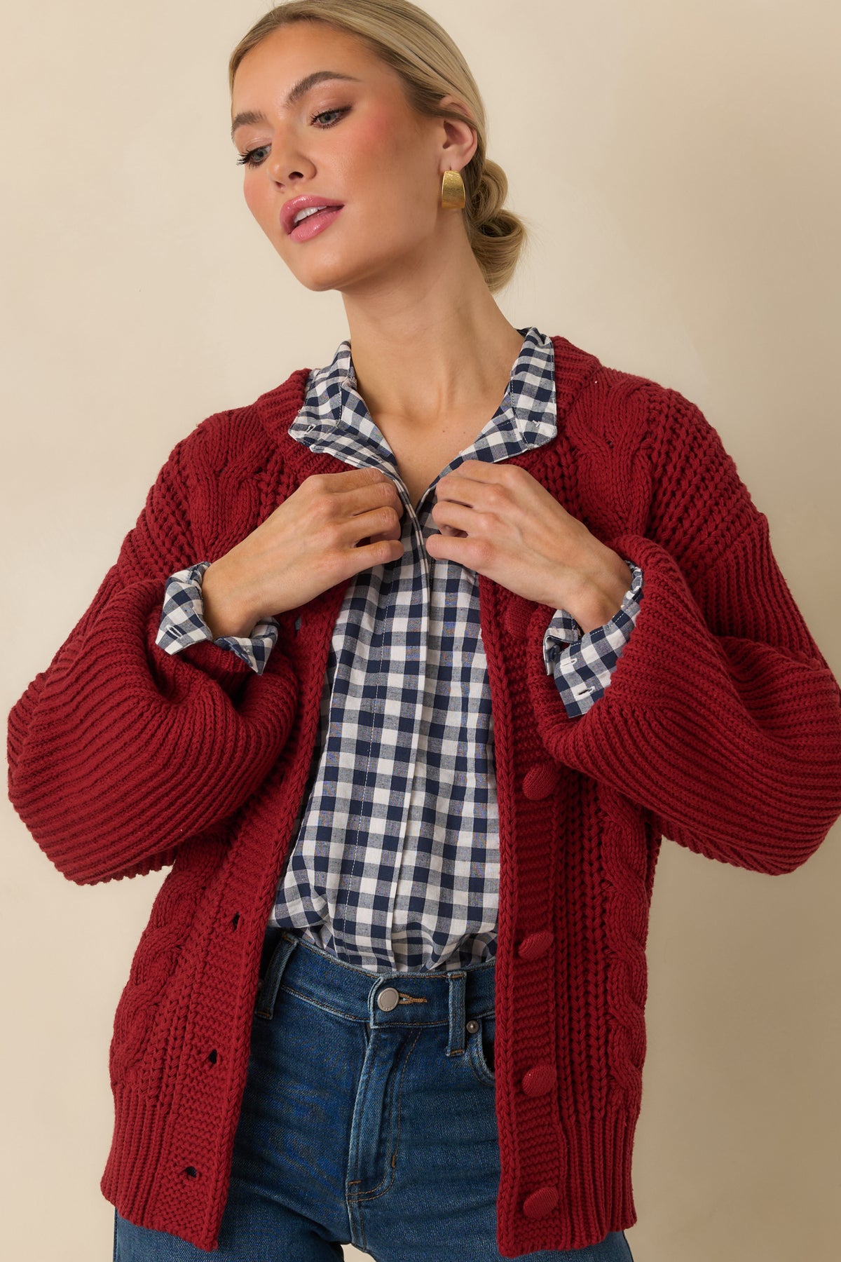 Burgundy cardigan featuring tonal knit-covered buttons against the textured cable-knit front and soft cotton-blend fabric.