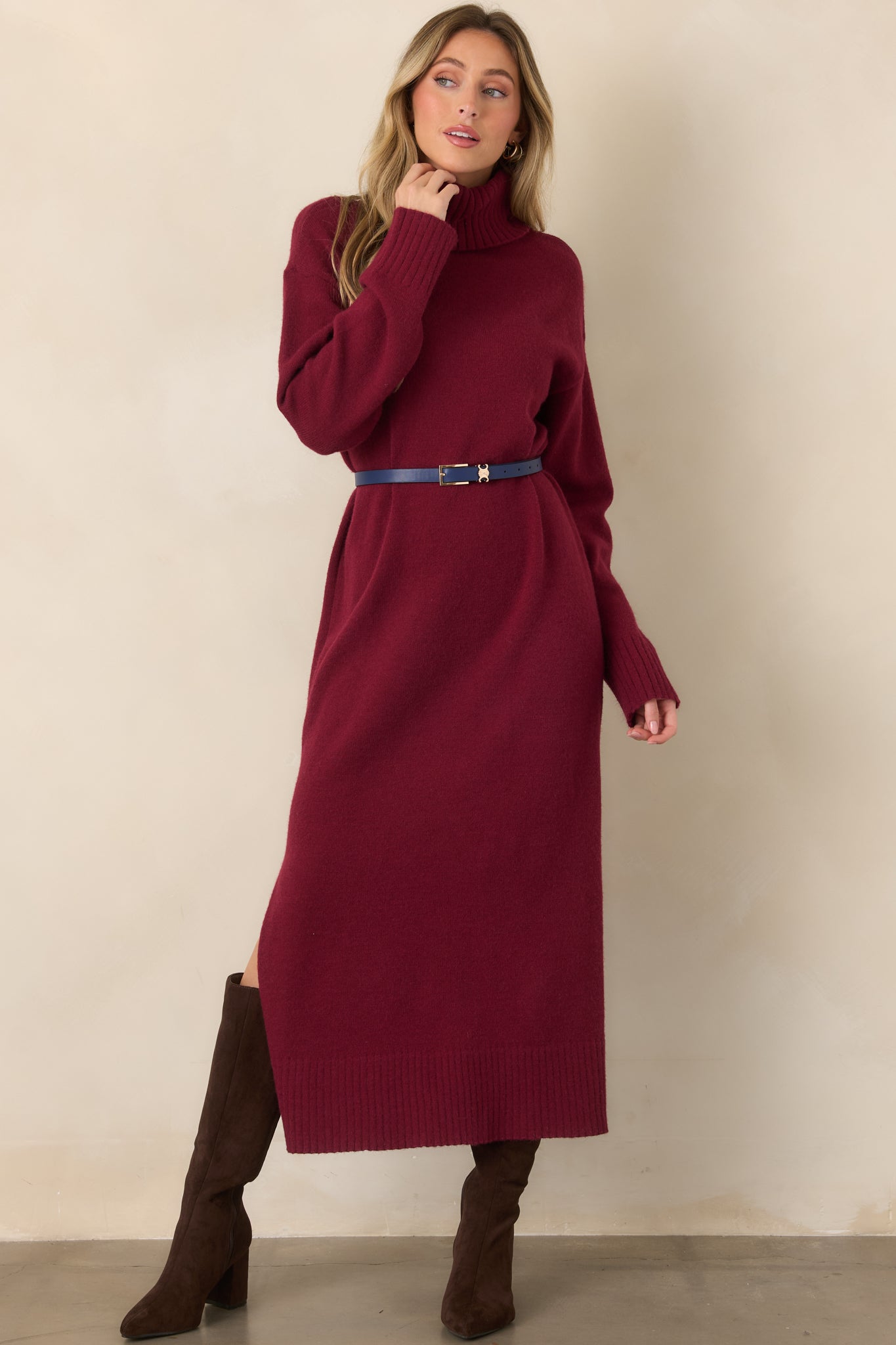 Burgundy knit sweater dress featuring a turtleneck neckline, long sleeves, midi length, soft stretch construction, and ribbed trim at the cuffs and hem.
