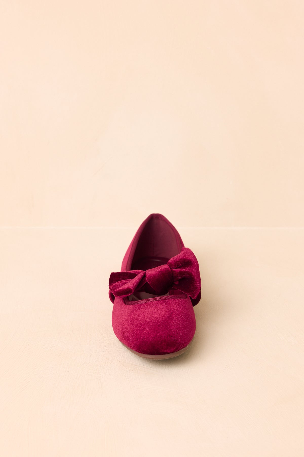 A low heel adds subtle height to these burgundy velvet flats with a bow-accented strap.