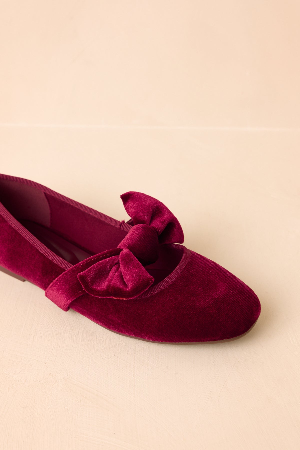 A statement bow decorates the strap of these classic burgundy velvet Mary Jane flats.