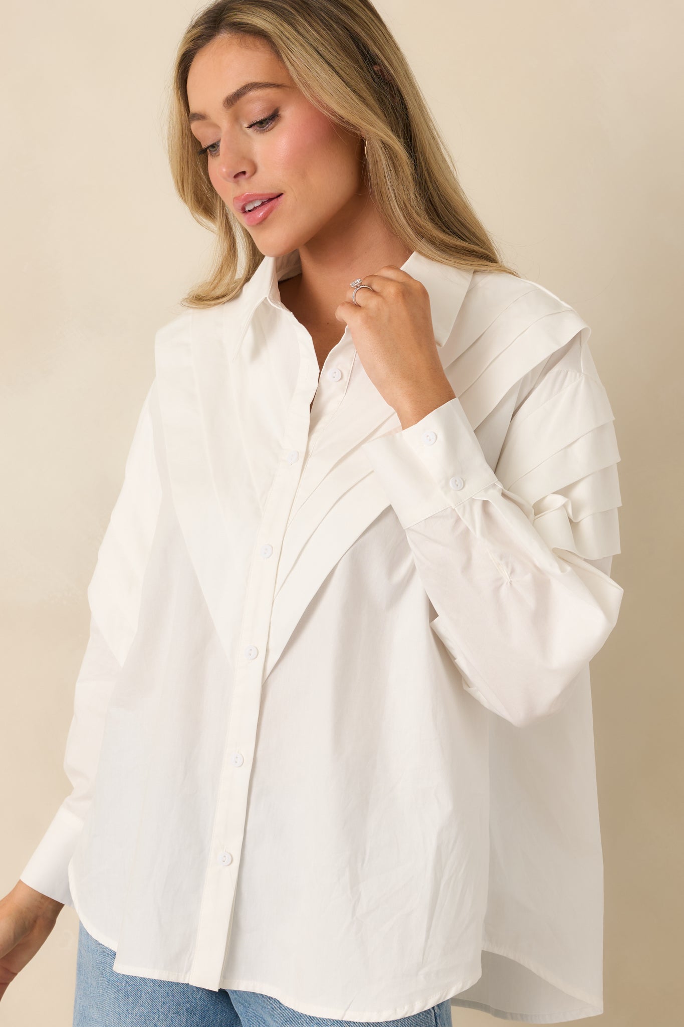 Buttoned cuff detail on the long sleeves of a white cotton woven blouse.