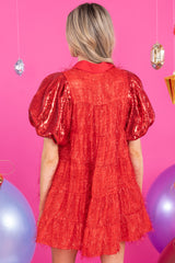 Back view of this dress that features a collared neckline, functional red buttons down the front, sequin puff sleeves, and sparkly tinsel throughout.
