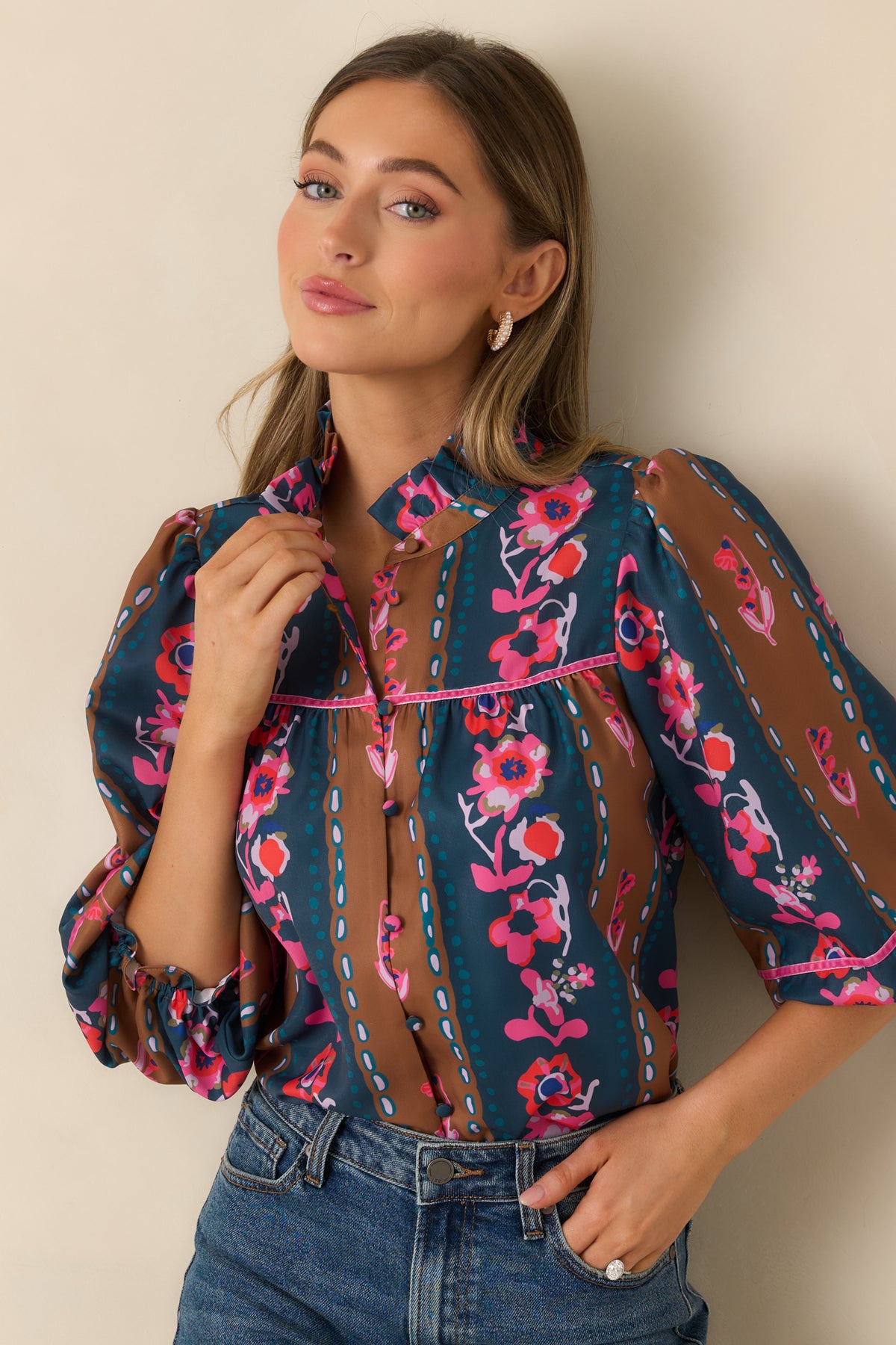 Ruffled stand collar and fabric-covered buttons accent the colorful striped floral blouse.