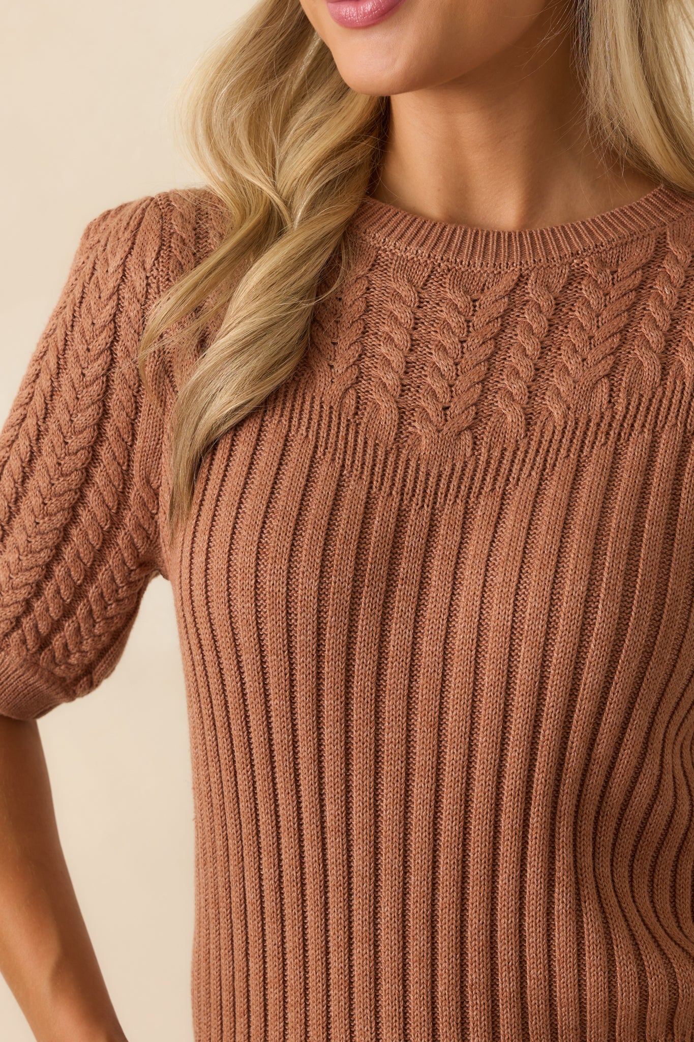 Cable knit stitches woven through the clay brown sweater’s yoke for added texture.
