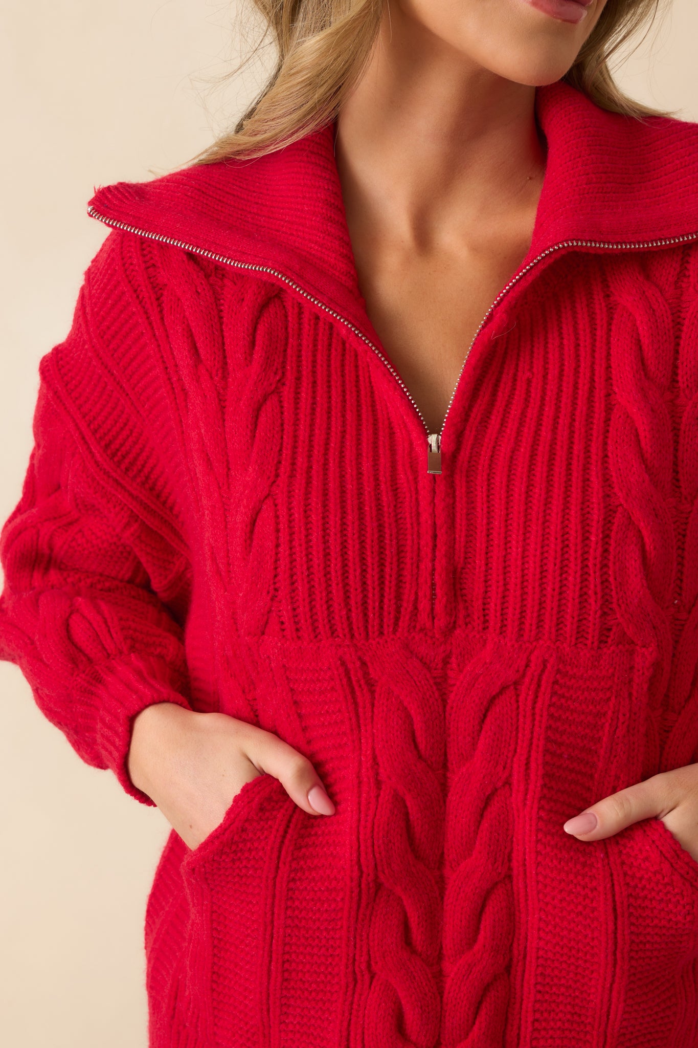 Detailed close-up of the cable knit texture, quarter zip, and fold-over collar.