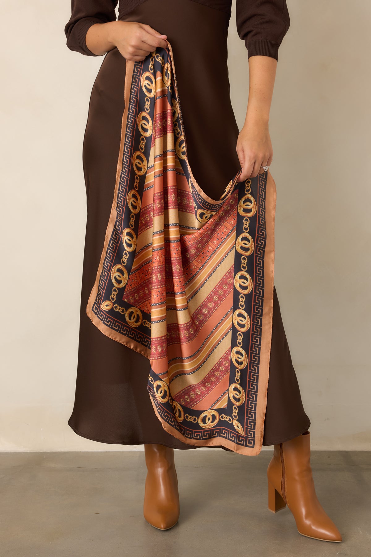Camel and black scarf featuring ornate golden chain motifs surrounded by rich rust and burgundy pattern accents.