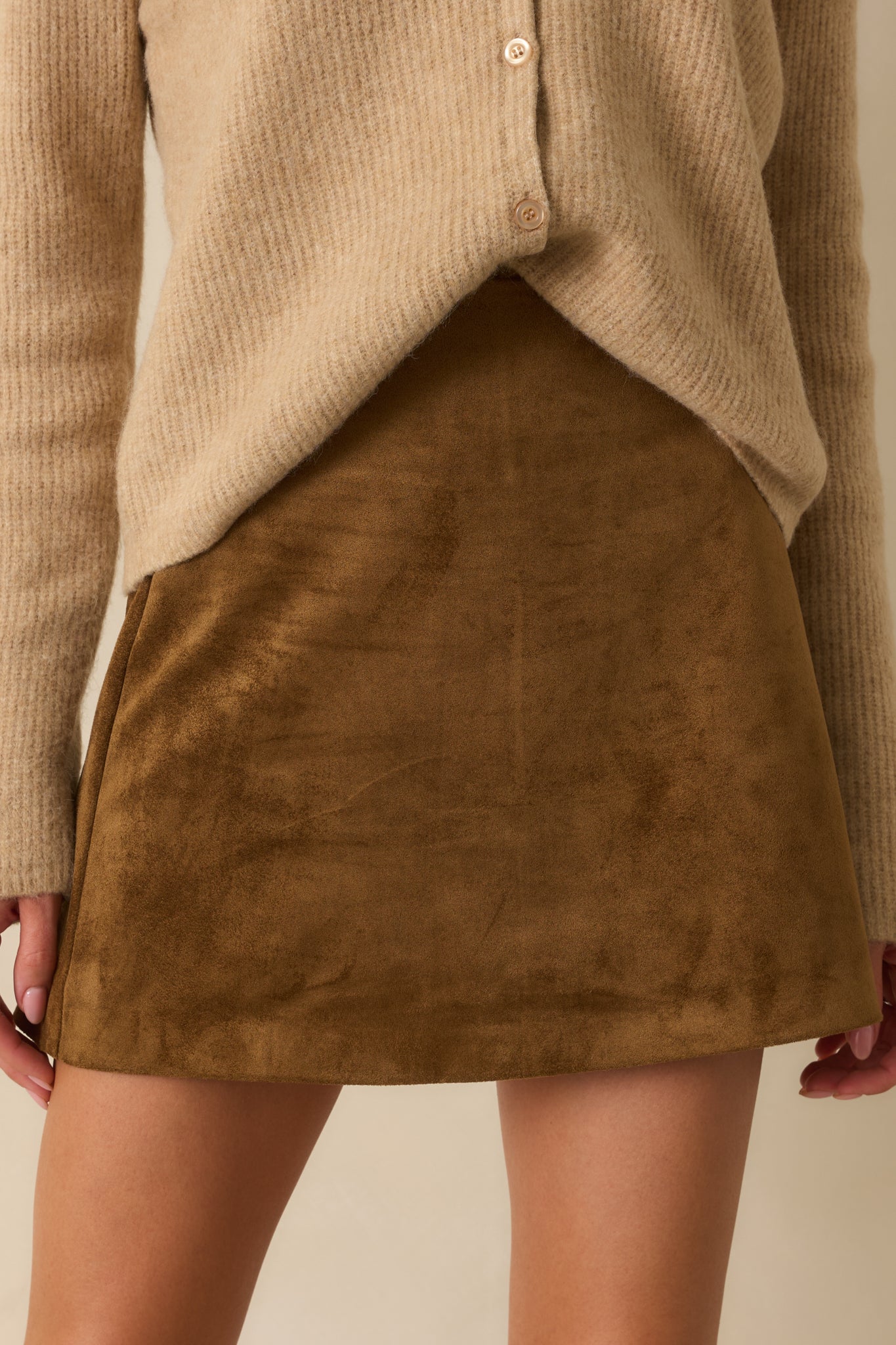 Detailed look at the faux suede texture and structured tailoring of the camel brown mini skirt.