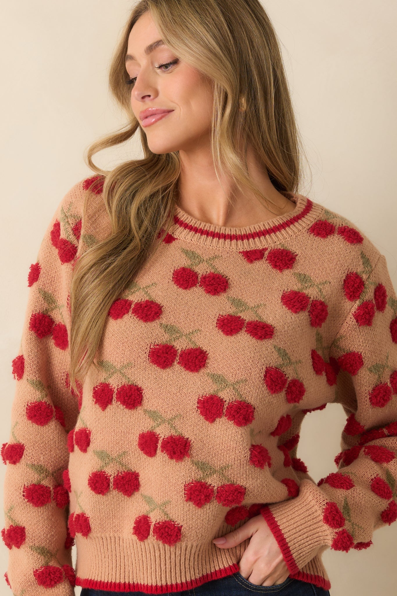 Close-up showing playful red chenille cherry motifs on the camel brown sweater.