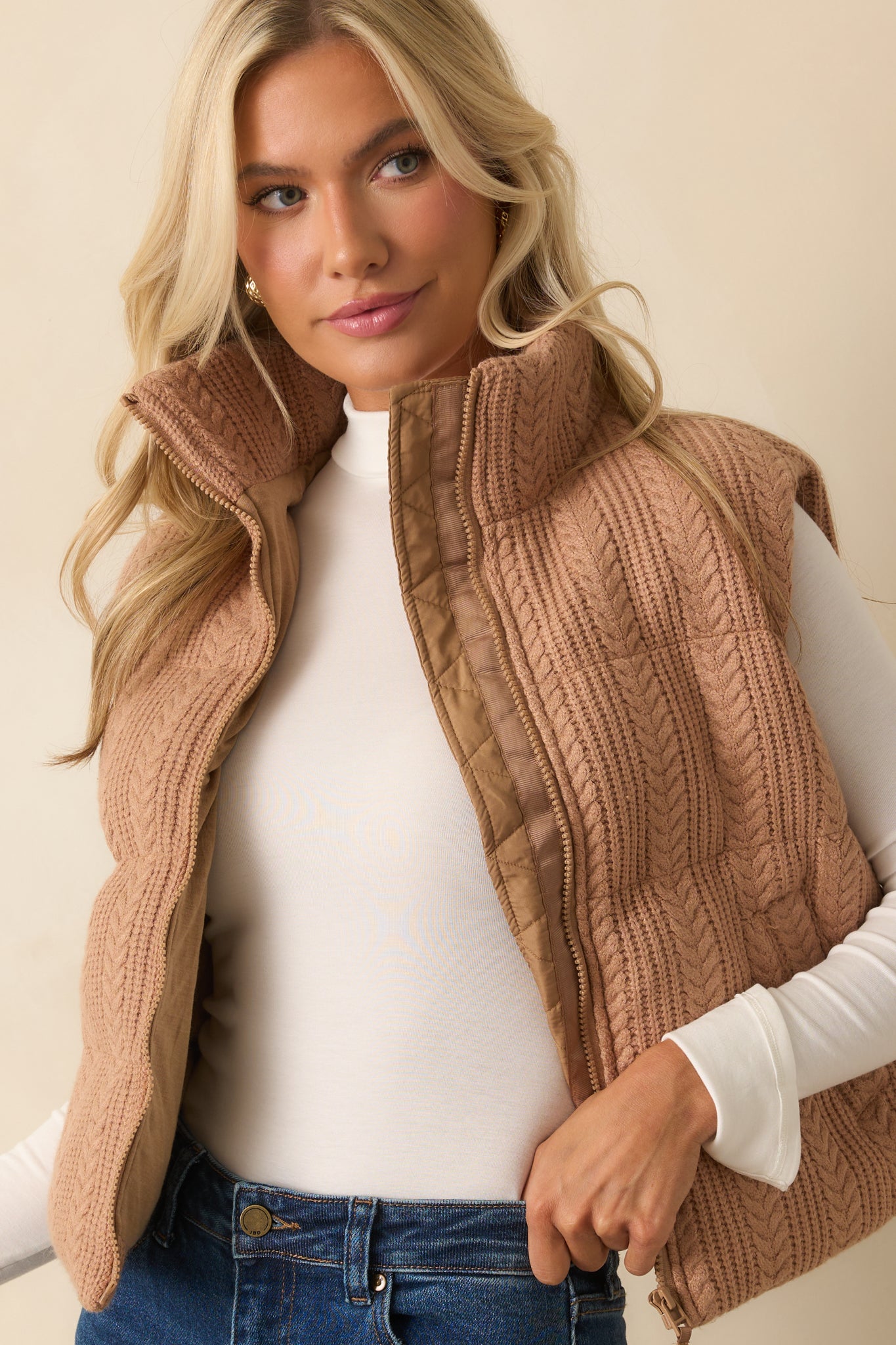 High stand collar highlighted on the camel brown sleeveless vest.