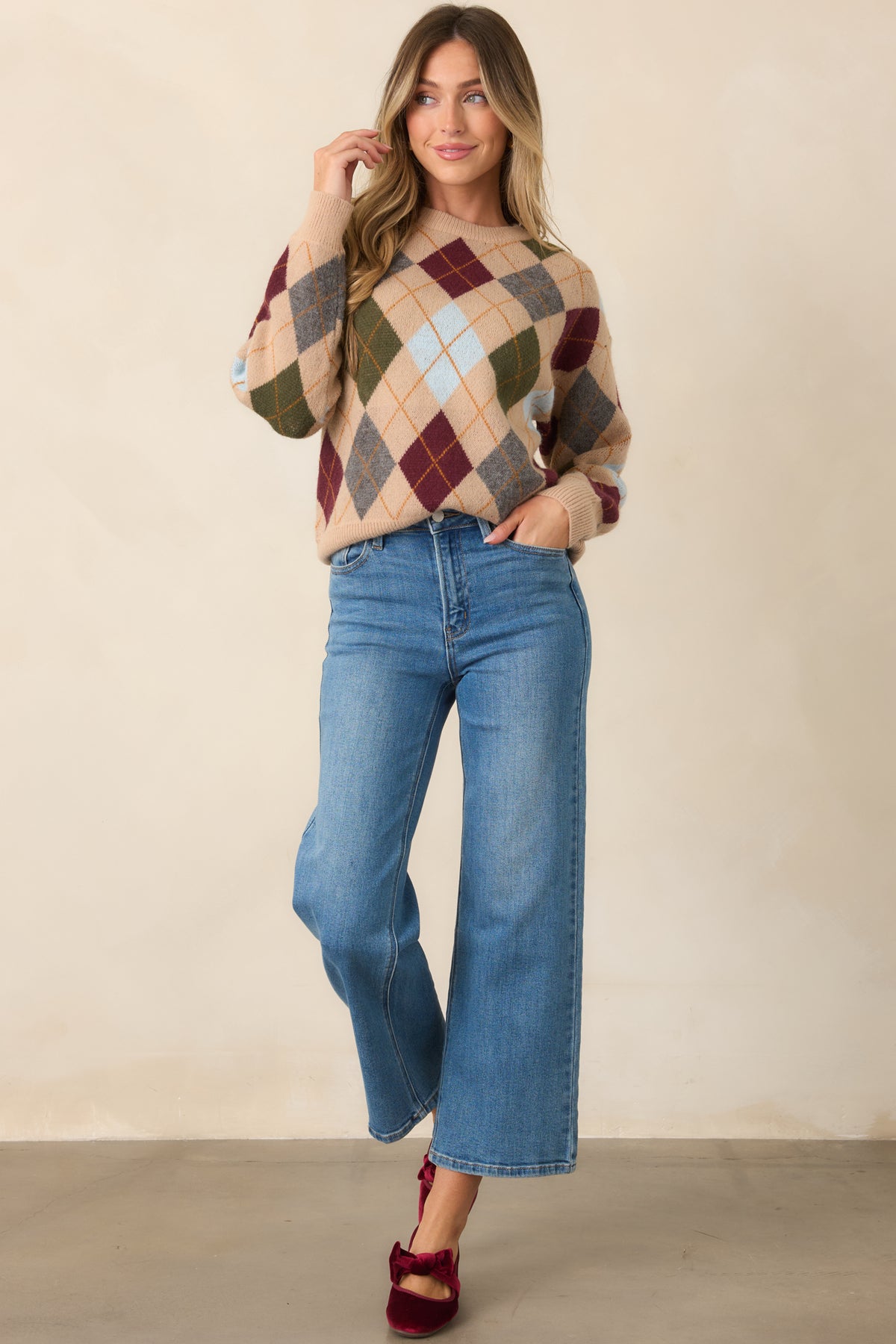 Burgundy and olive diamond motifs combine with grey, light blue, and golden accents throughout the camel knit.