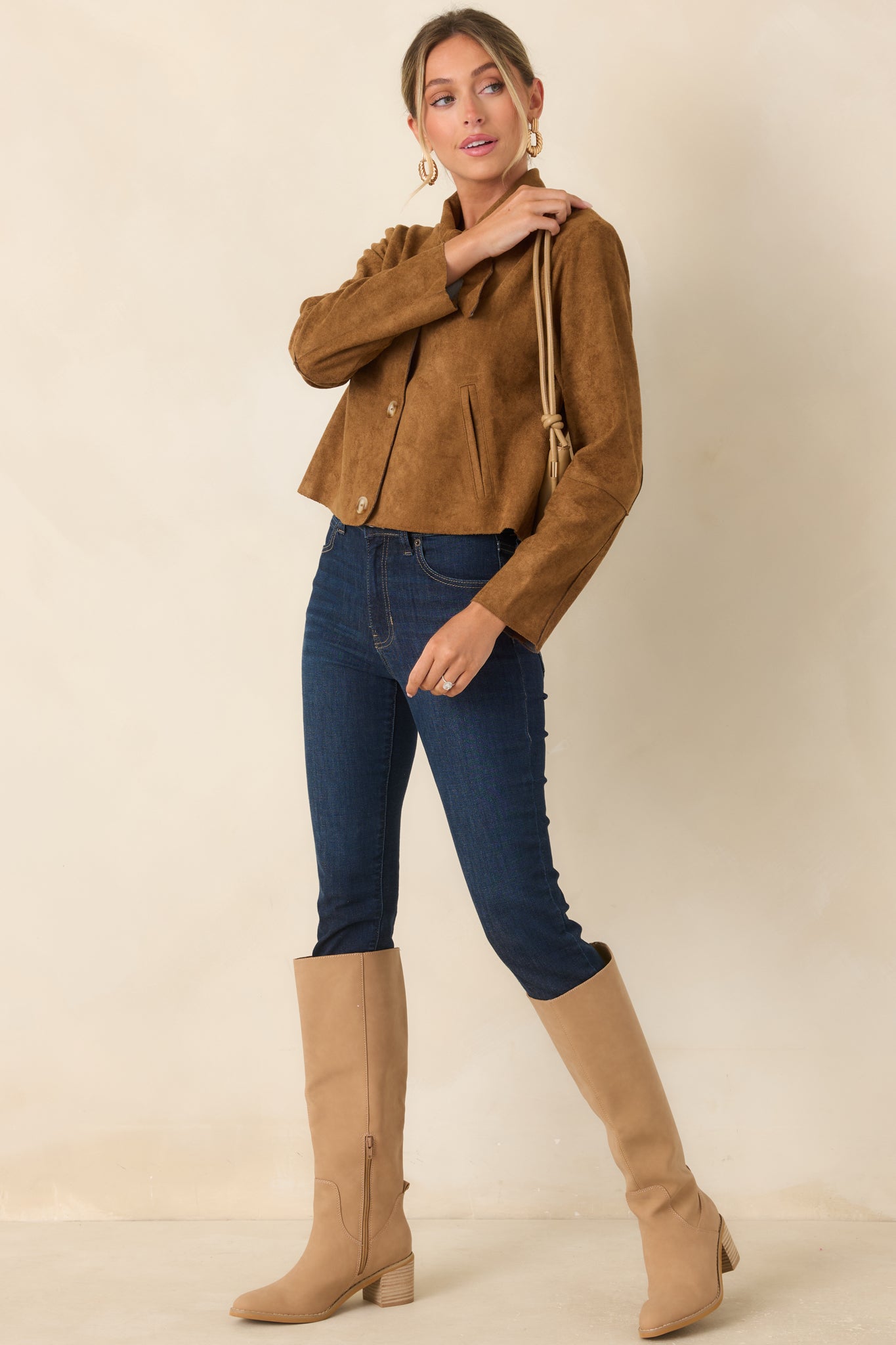 Camel faux suede jacket showcasing a cropped length, delicate tie neckline, button-front design, long sleeves, and subtle welt pockets.