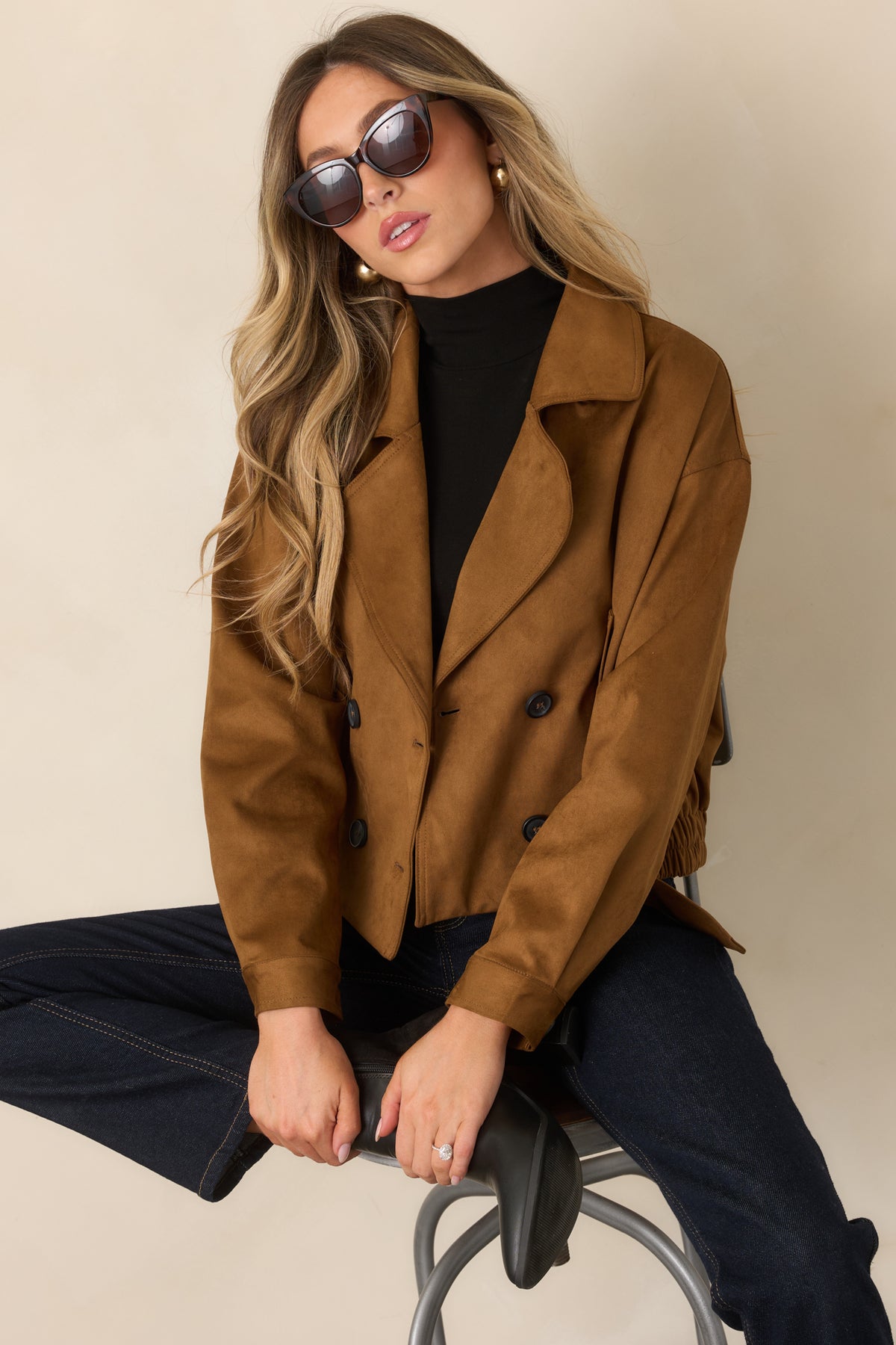 Camel cropped trench coat showcasing the front pockets and double-breasted closure.