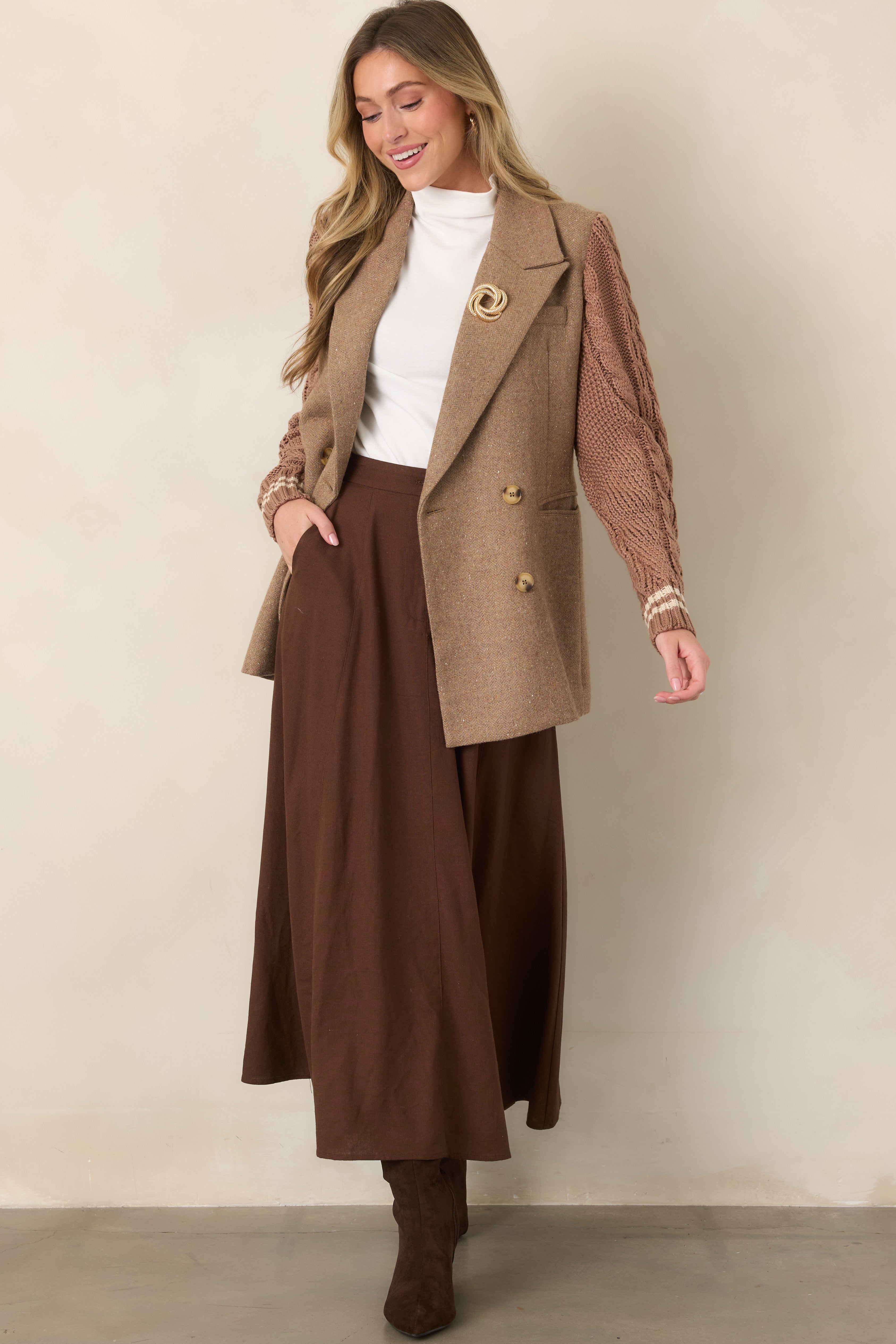 Structured camel blazer with a double-breasted button front, contrasting textured sleeves, striped cuff detailing, and mid-thigh length.