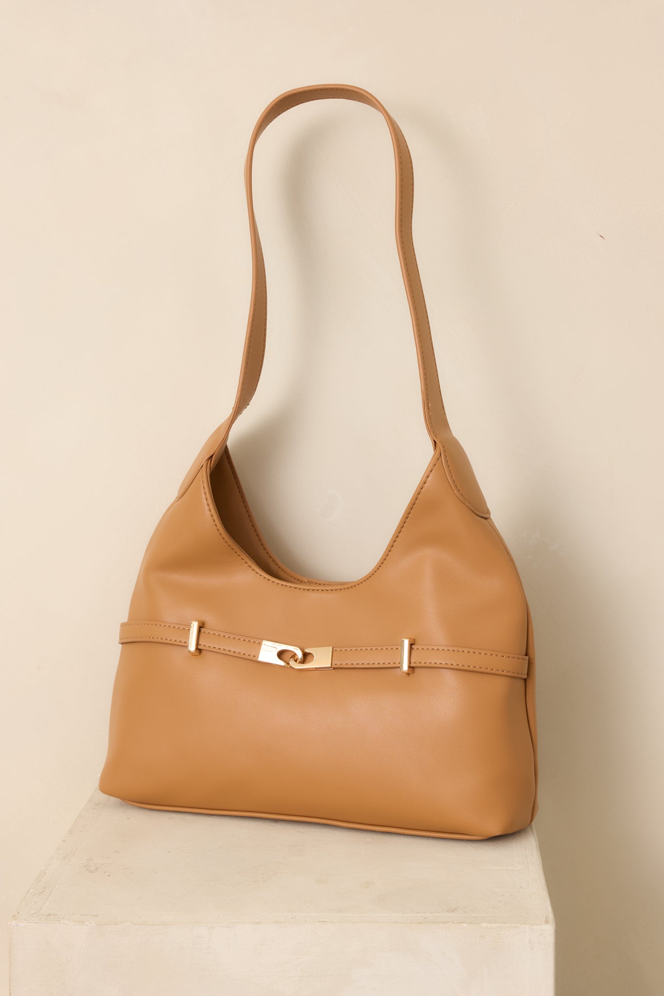 Camel faux leather shoulder bag with a softly structured silhouette, smooth finish, polished gold-tone hardware, and a magnetic snap closure.