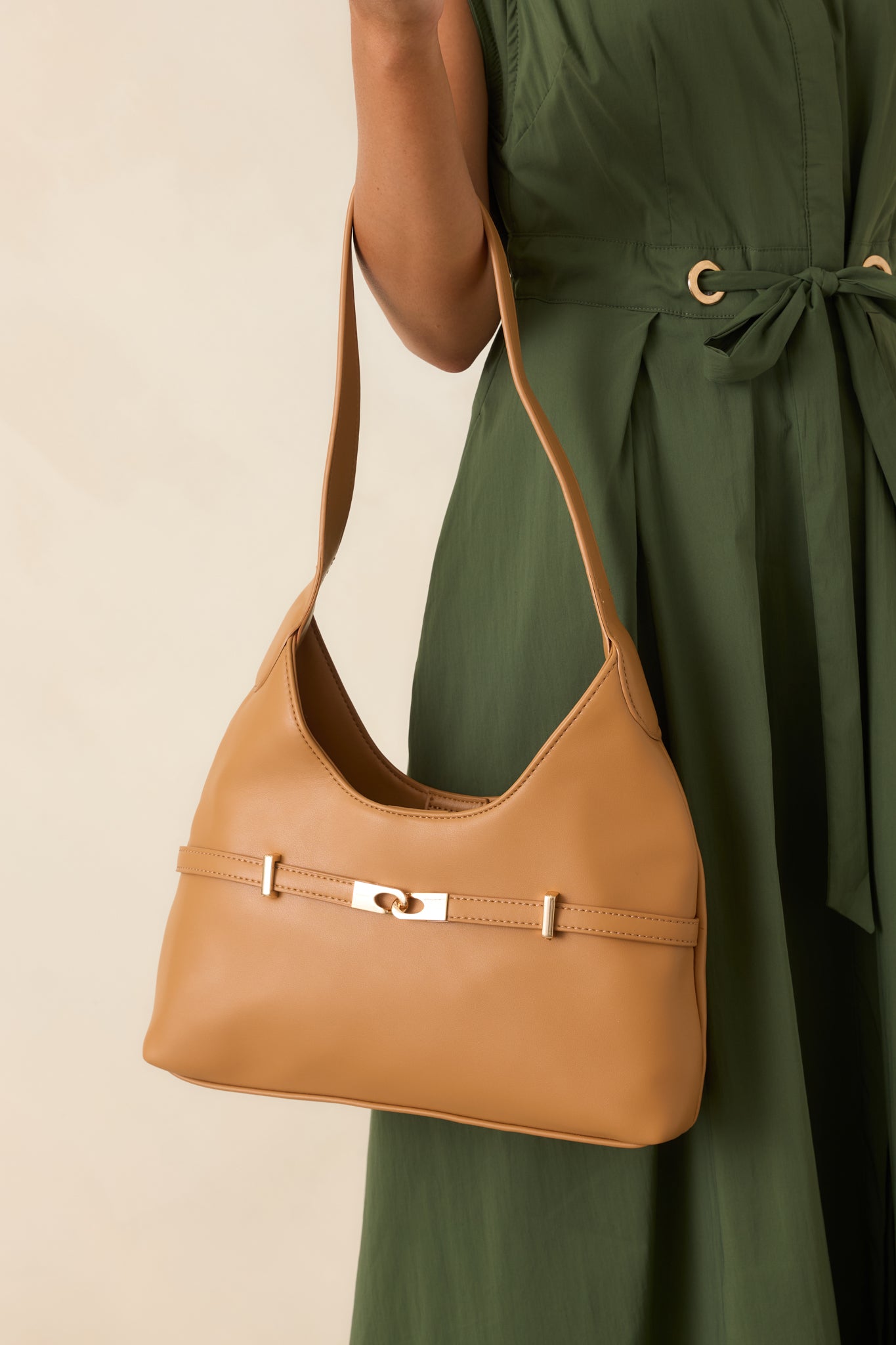 Camel faux leather shoulder bag featuring a softly structured silhouette, gold-tone hardware, and a spacious single compartment.
