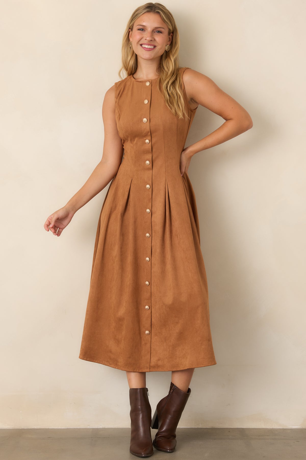 Camel faux suede dress showcasing a streamlined sleeveless bodice, ornate gold-tone button row, tailored seams, and a textured pleated midi skirt.