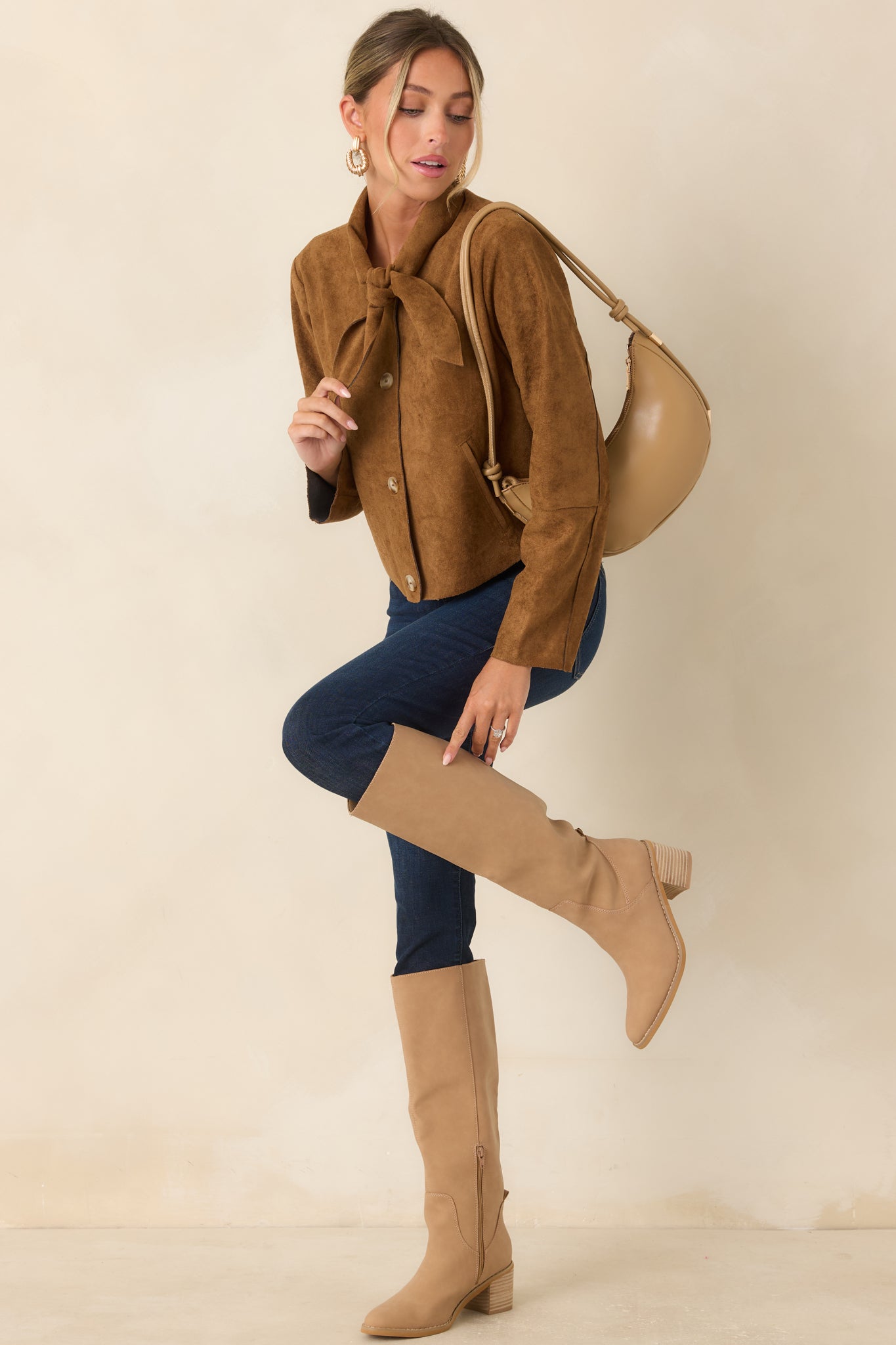 Soft camel faux suede cropped jacket featuring a feminine tie neckline, front button closure, long sleeves, and a lightly structured silhouette.