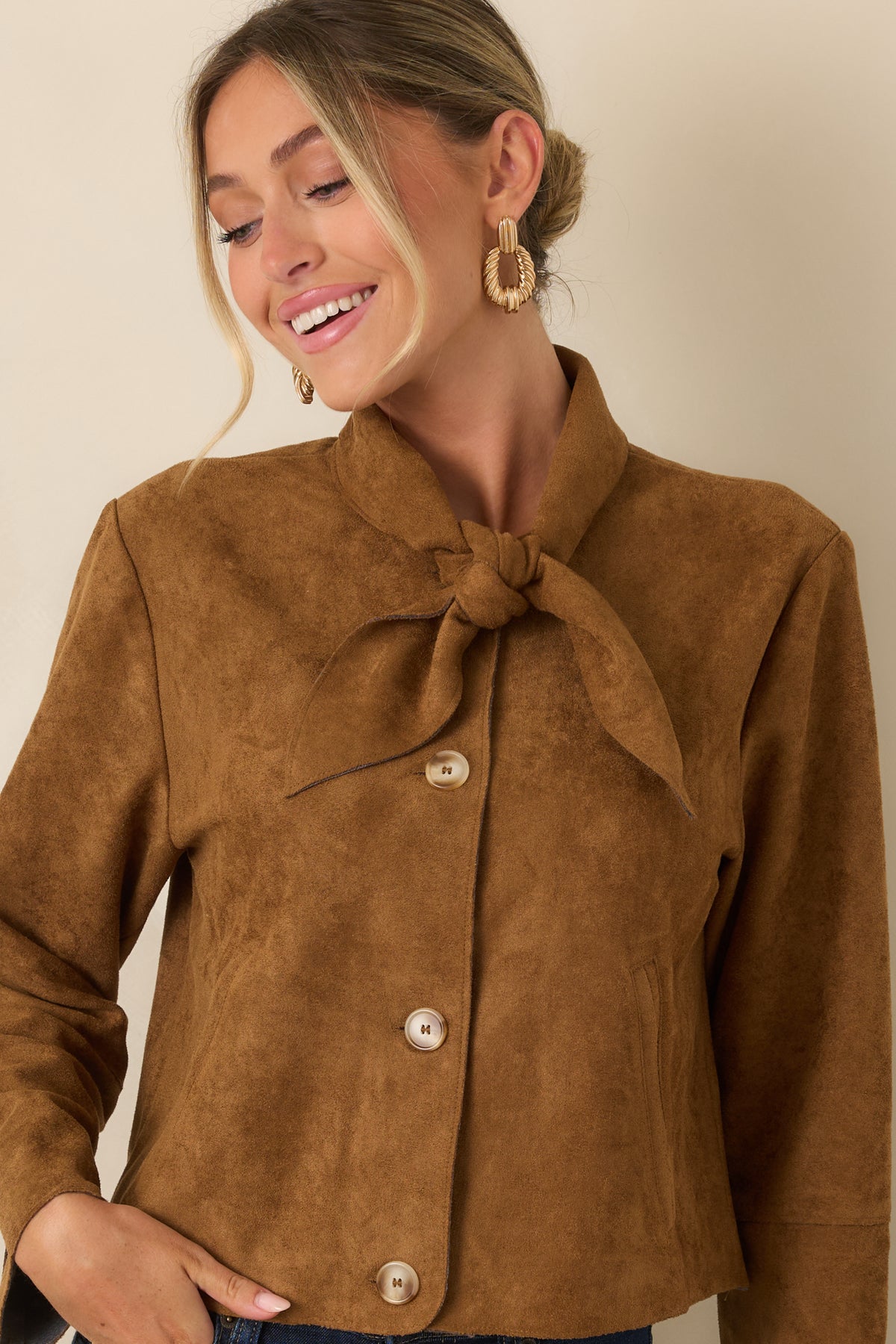Cropped view of the jacket featuring the feminine tie neckline, long sleeves, smooth suede finish, and tailored front design.