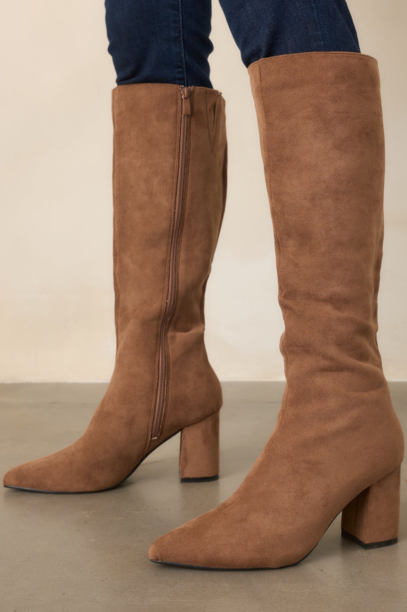 Camel tall boots featuring a sleek pointed toe, fitted shaft, and smooth covered block heel for a polished finish.