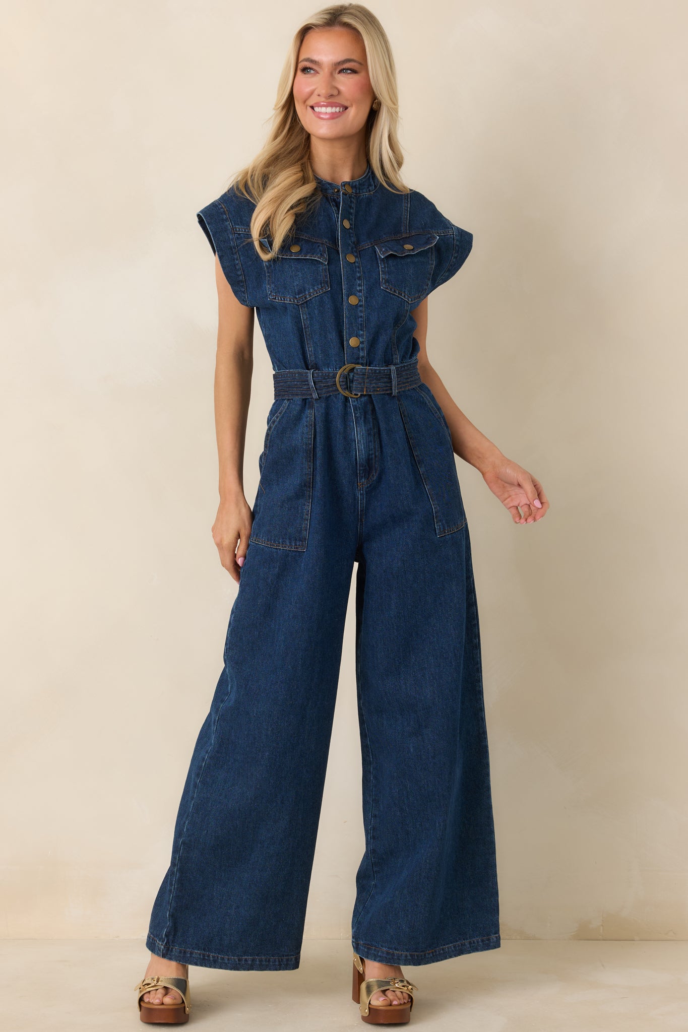 Cap-sleeve jumpsuit with adjustable waist belt, metal buckle accent, and relaxed wide-leg fit.