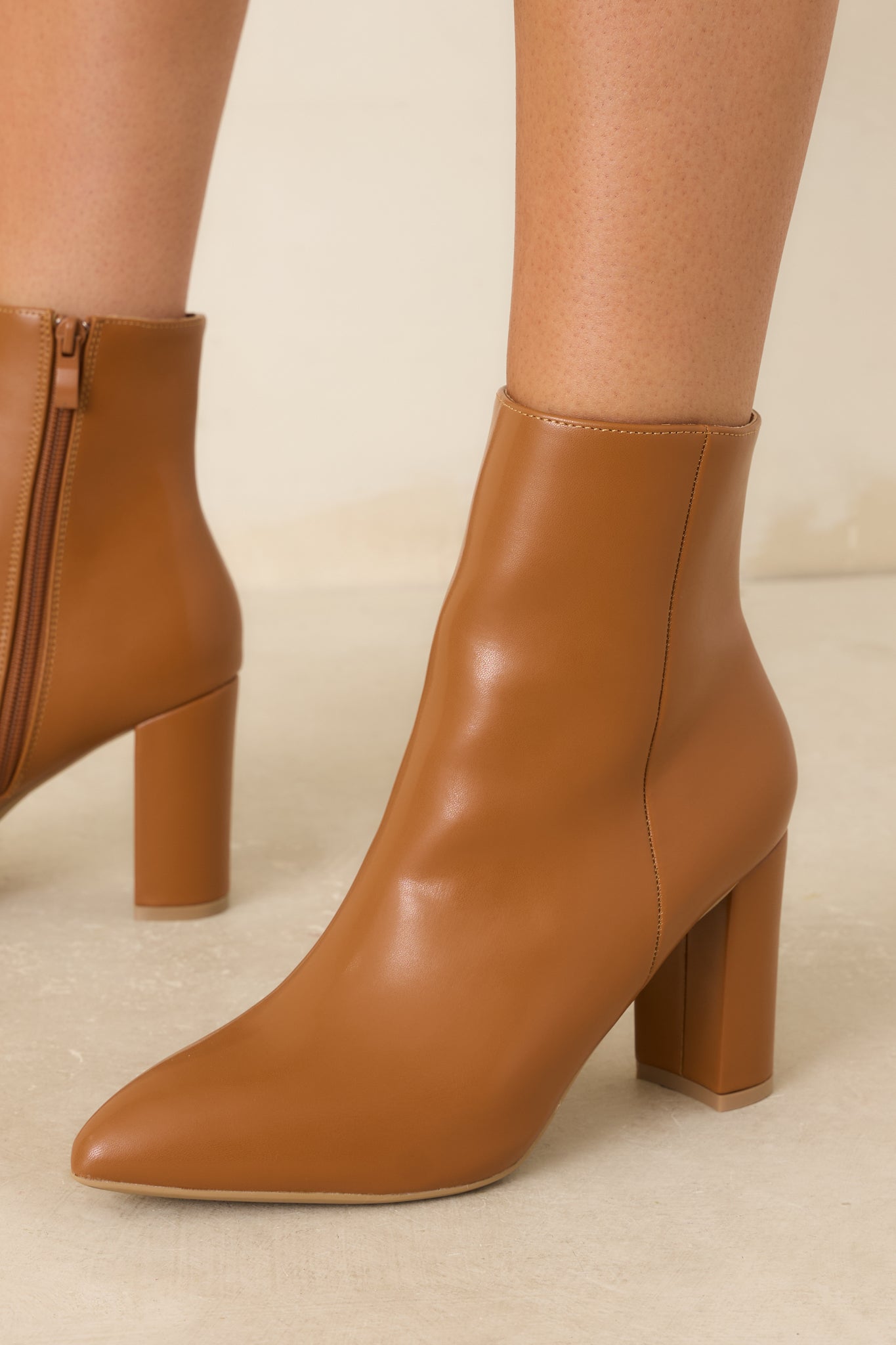 Caramel brown ankle boots featuring a pointed toe, faux leather construction, and a sturdy block heel.