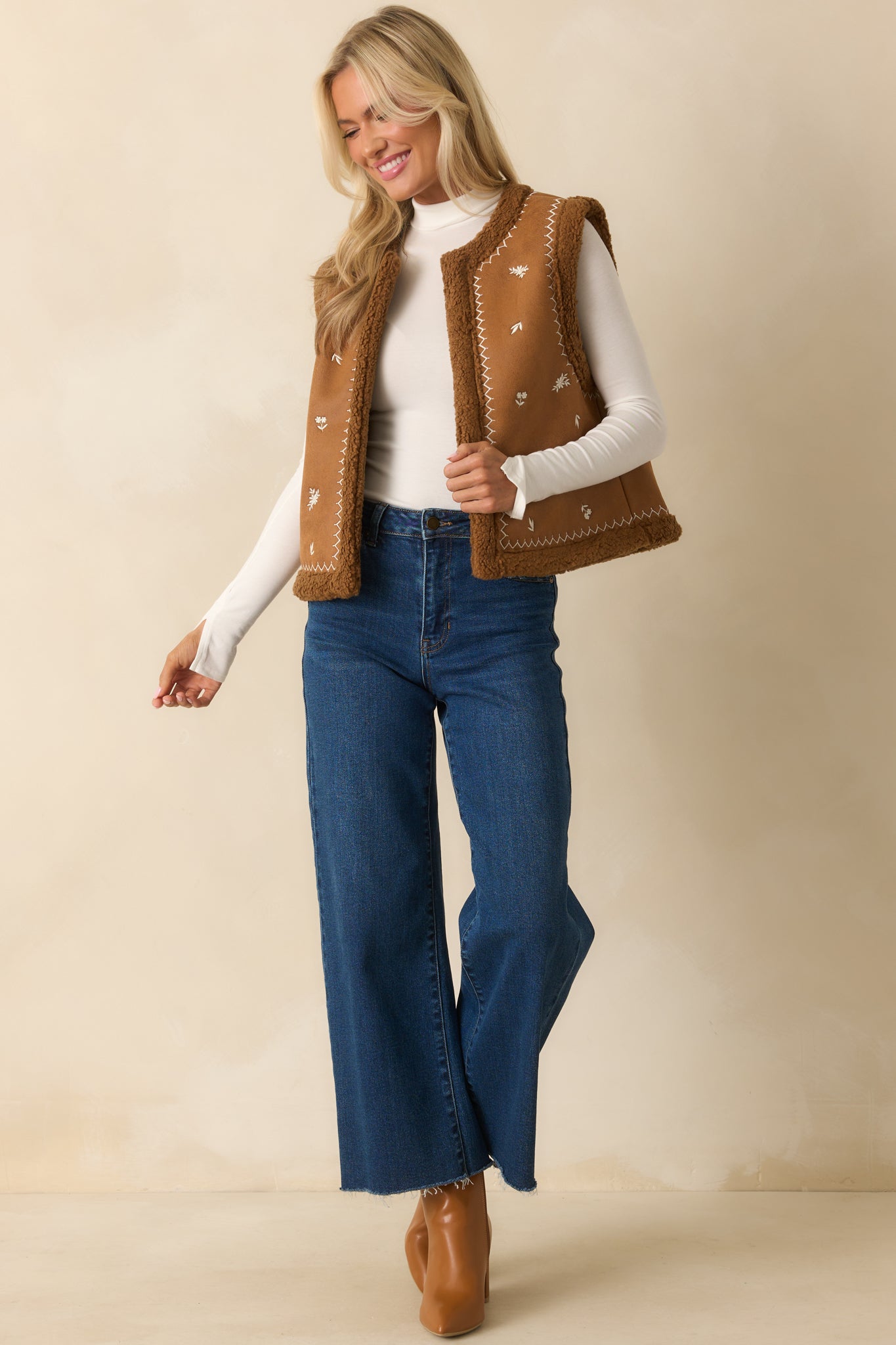 Caramel brown faux suede vest with ivory floral embroidery, open front, and straight hem.