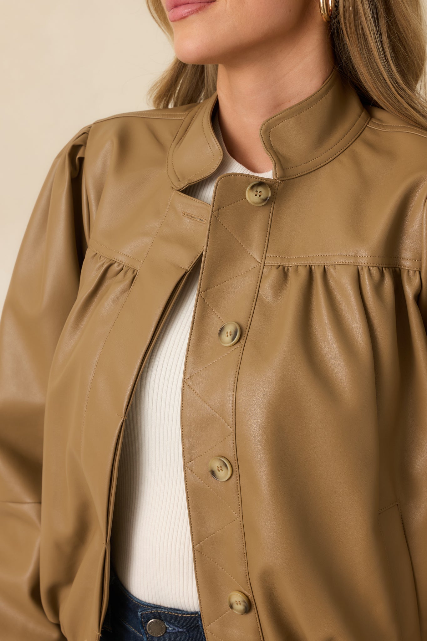 Close-up detail of the jacket showing geometric quilted stitching, fabric-covered? button-front accents, and smooth vegan leather.