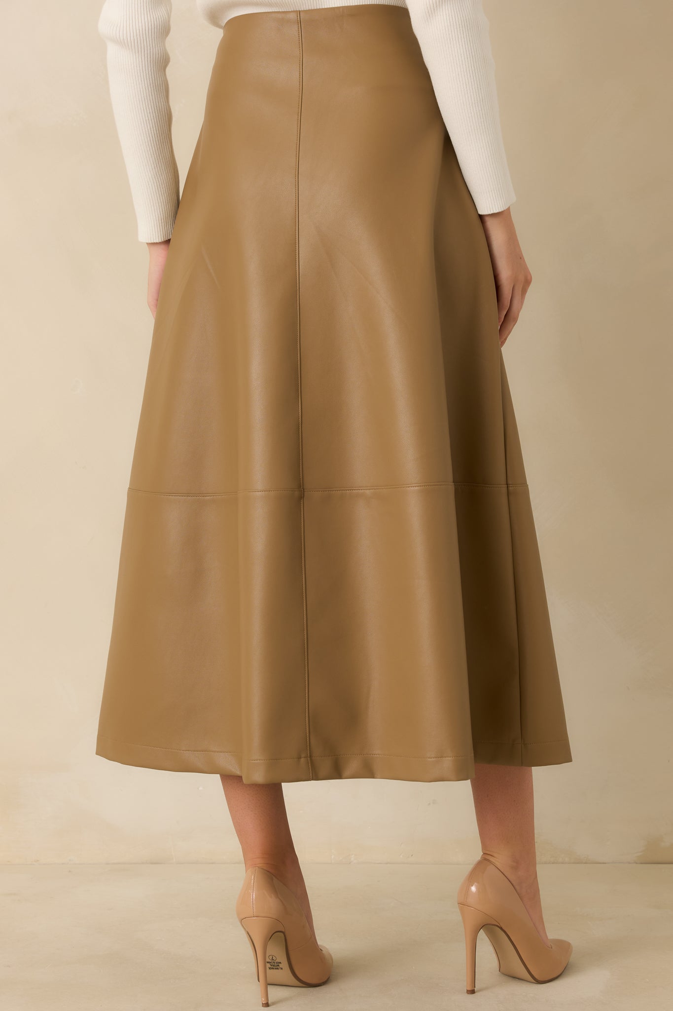 Rear view of the caramel vegan leather skirt highlighting its flared midi silhouette and clean panel construction.