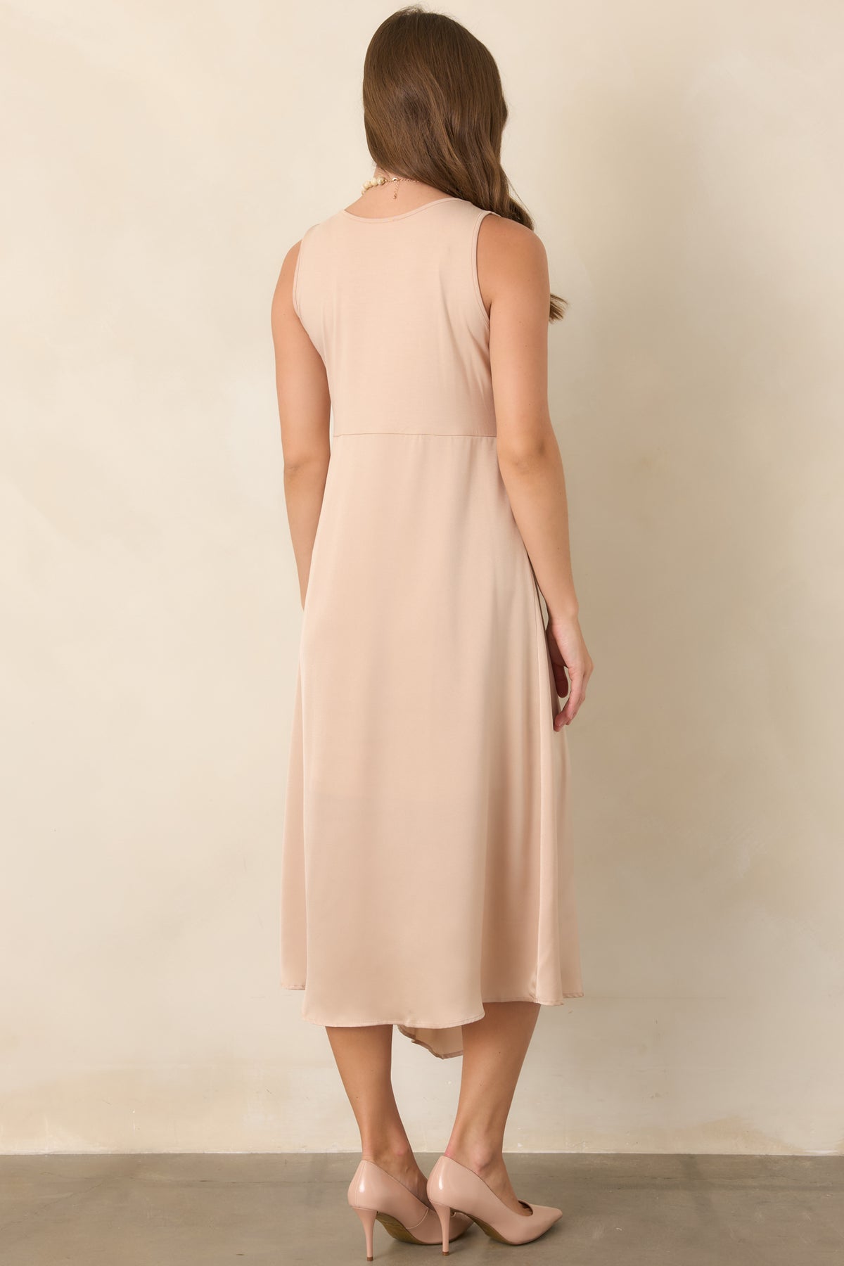 Rear view of the champagne midi dress showcasing its sleeveless knit bodice and flowing satin skirt with a smooth, elegant drape.