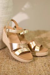These gold and bronze heels feature a rounded toe, an ankle strap, and a wedged heel.