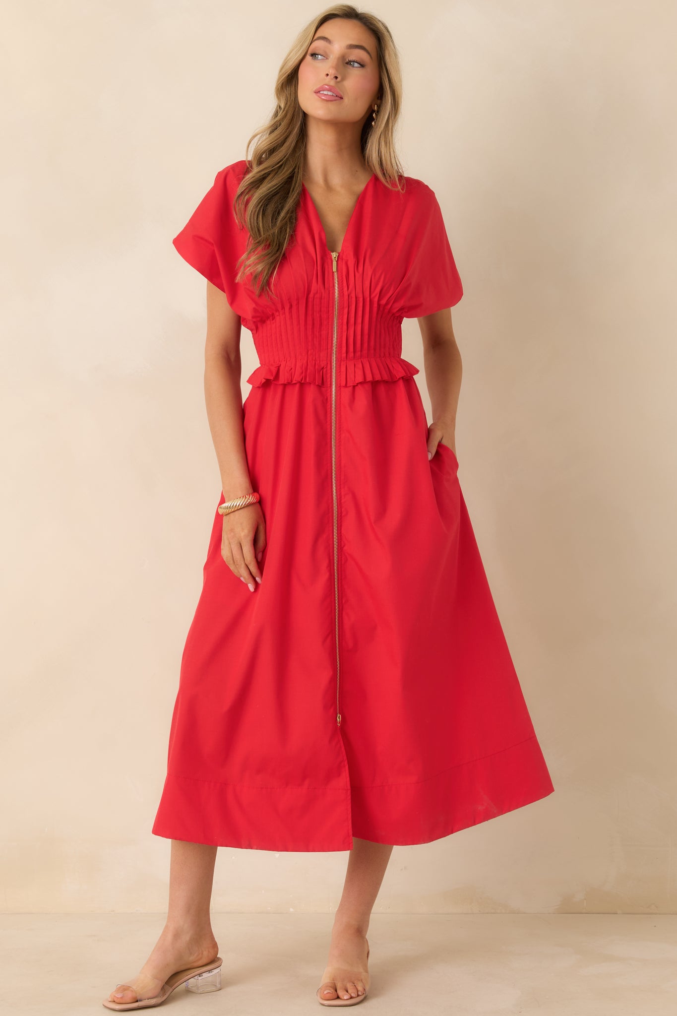 Cherry red woven dress in maxi length showcasing a smocked waistband with ruffle edging and functional side pockets.