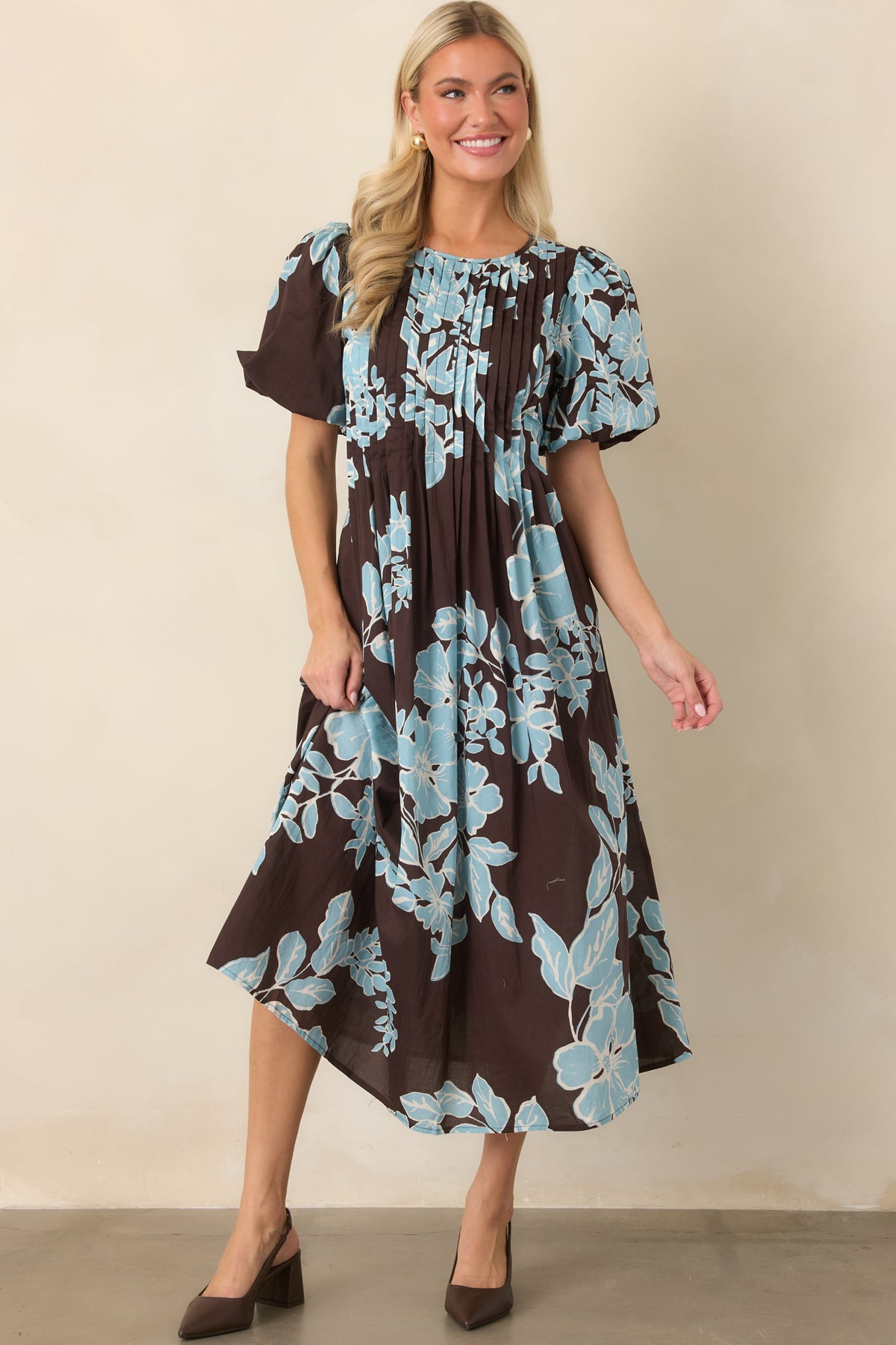 Chocolate and blue floral dress showcasing its defined waist, puff sleeves, and flowing midi-length skirt.