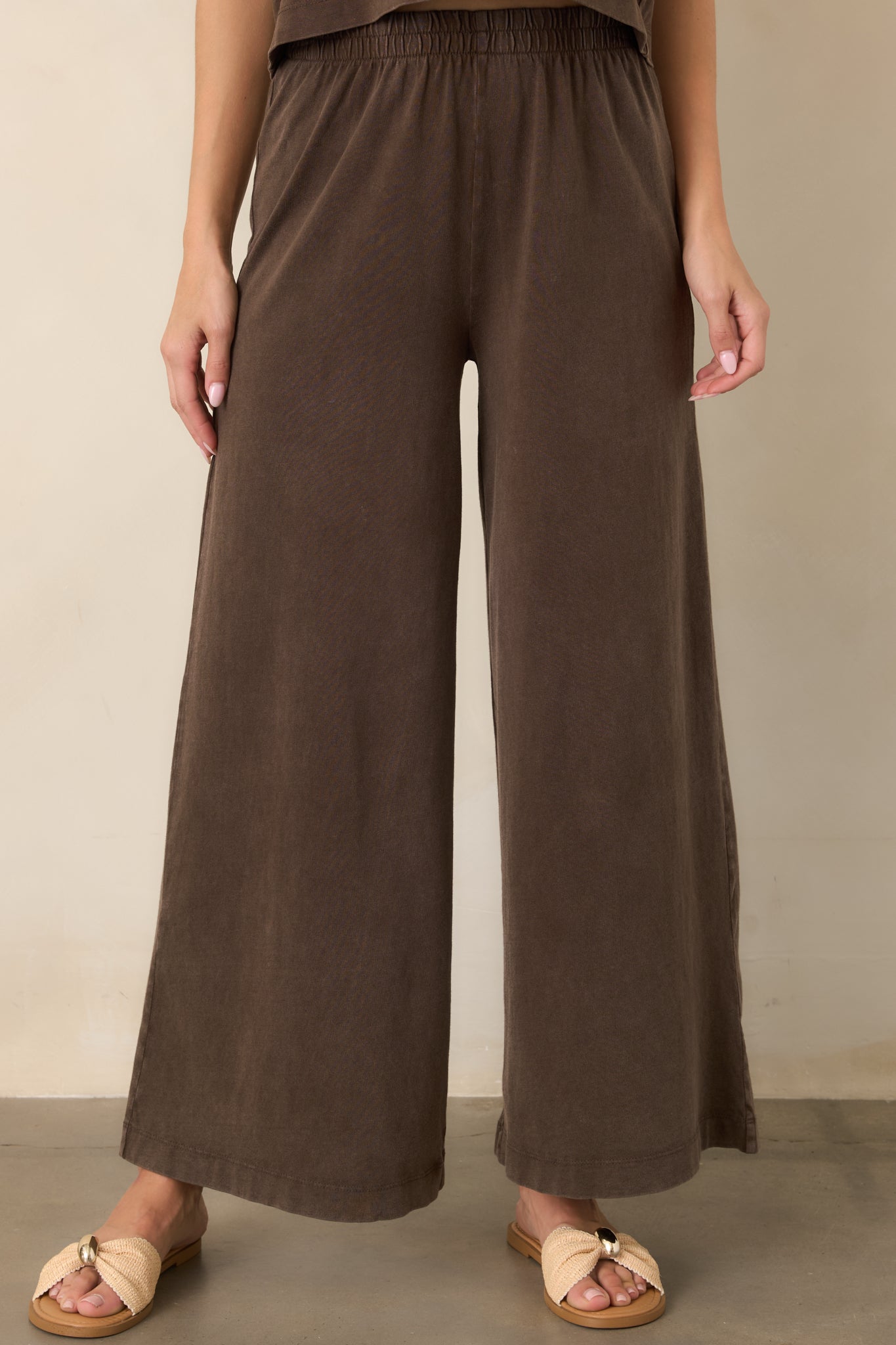 Close view of the dark chocolate brown pants highlighting the elastic waistband and relaxed fit through the upper portion.