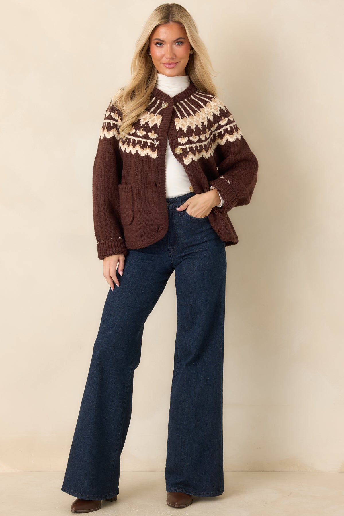 Chocolate brown knit cardigan with a cream and caramel Fair Isle pattern, gold-tone buttons, and two front patch pockets.